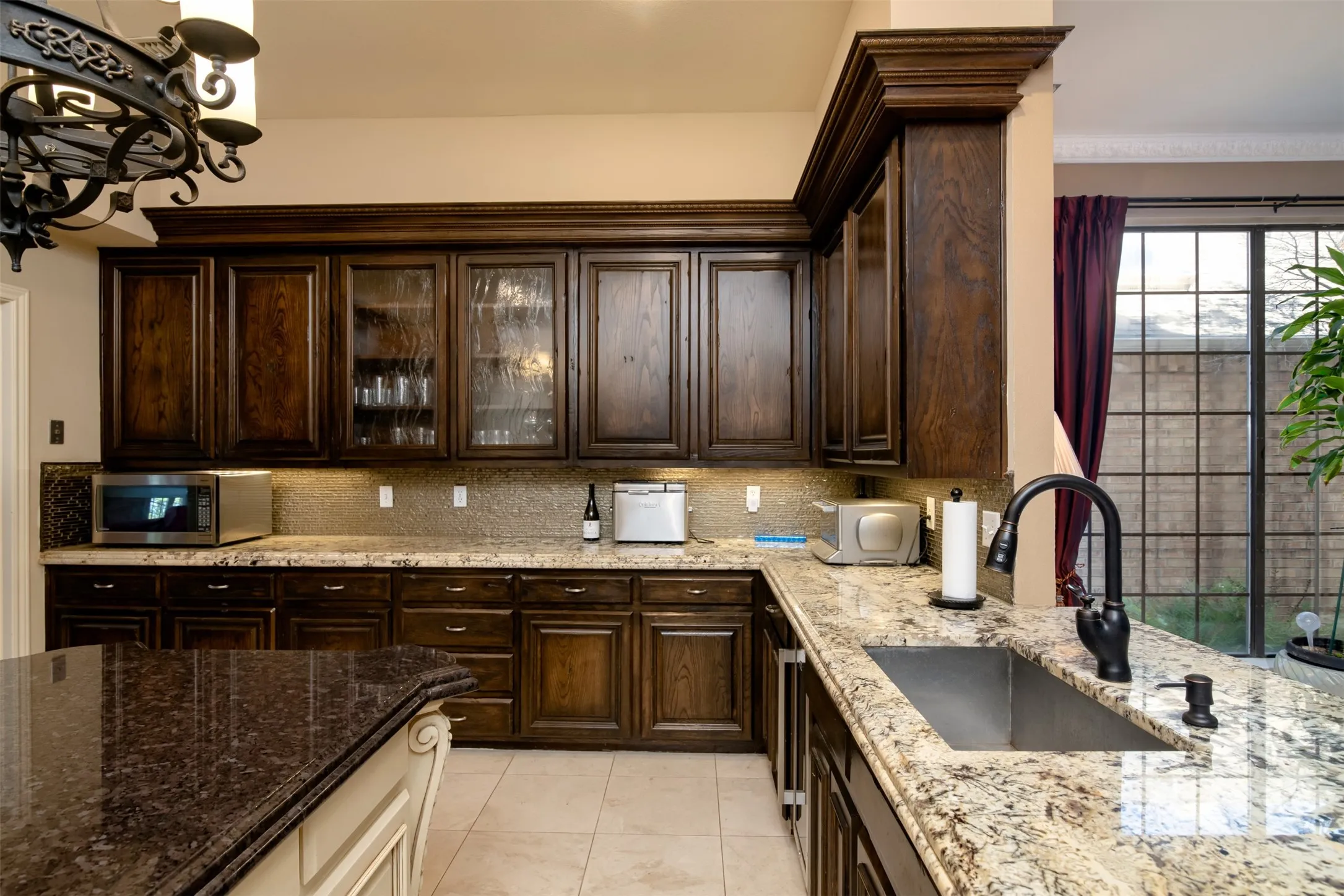 Kitchen featuring dark wood cabinetry, light-toned granite countertops, and a single-basin undermount sink with a matte black gooseneck faucet