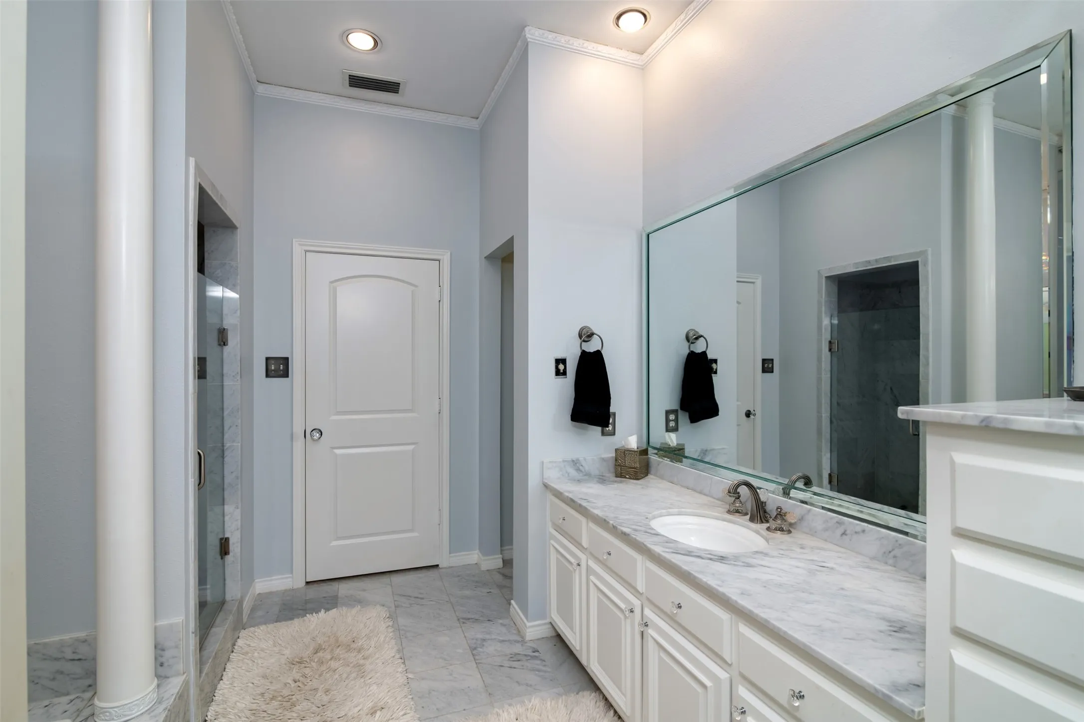 Bathroom vanity featuring a single undermount sink, a stone countertop, and an expansive wall-mounted mirror