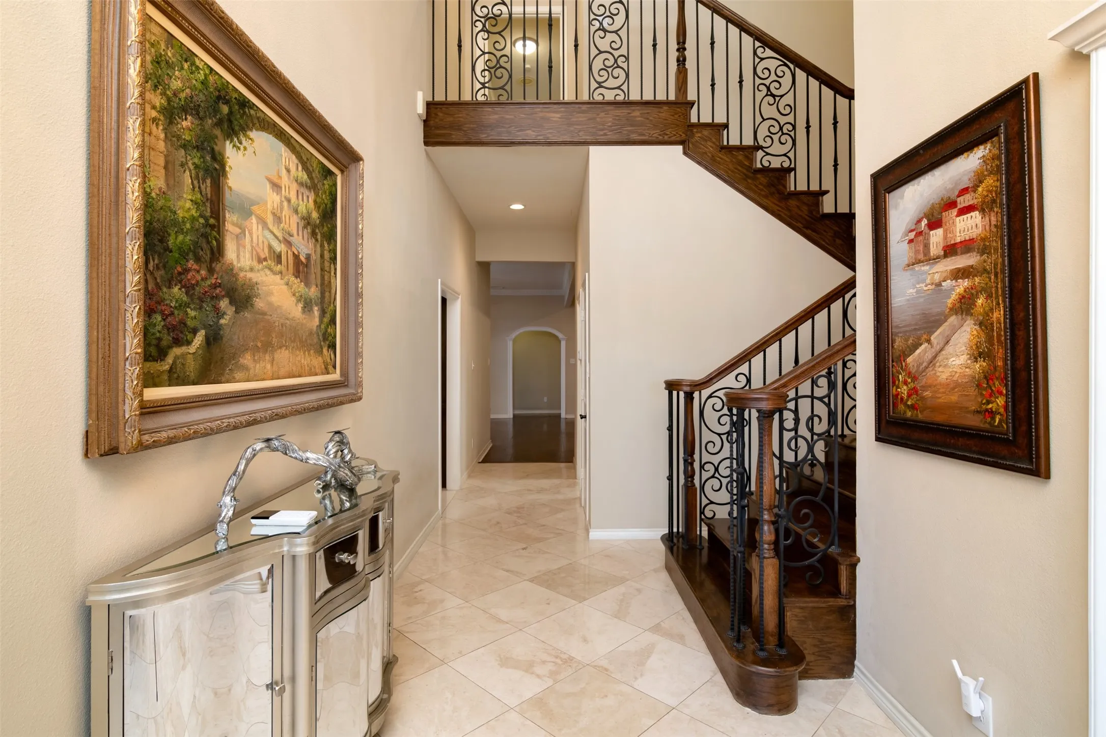 Foyer featuring a grand staircase with dark wood-finish treads and risers, ornate wrought iron balusters, and a matching wood-finish handrail