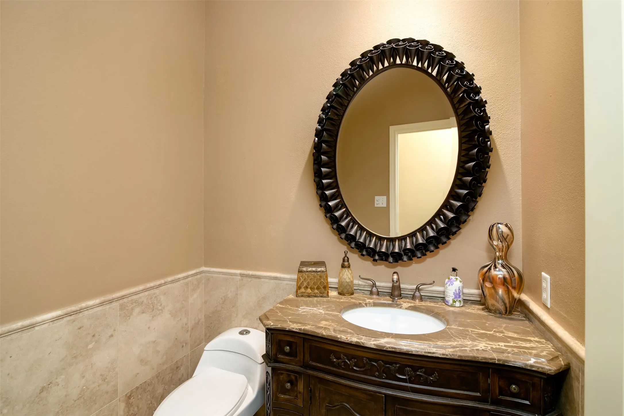 Powder room featuring a carved wood vanity with an integral sink and a stone countertop