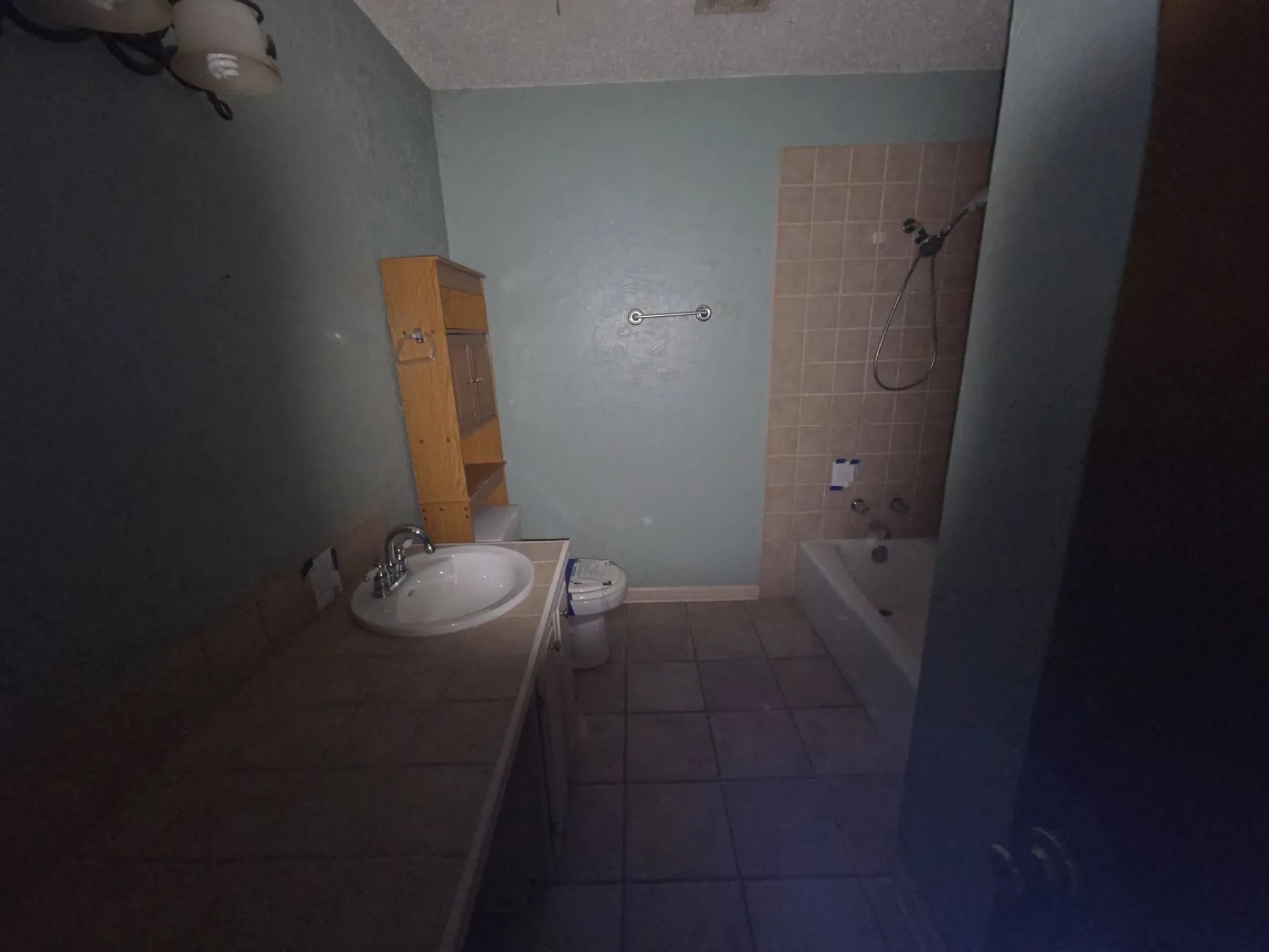 Bathroom featuring a built-in vanity with an integrated sink, a commode, and a tub with tiled surround