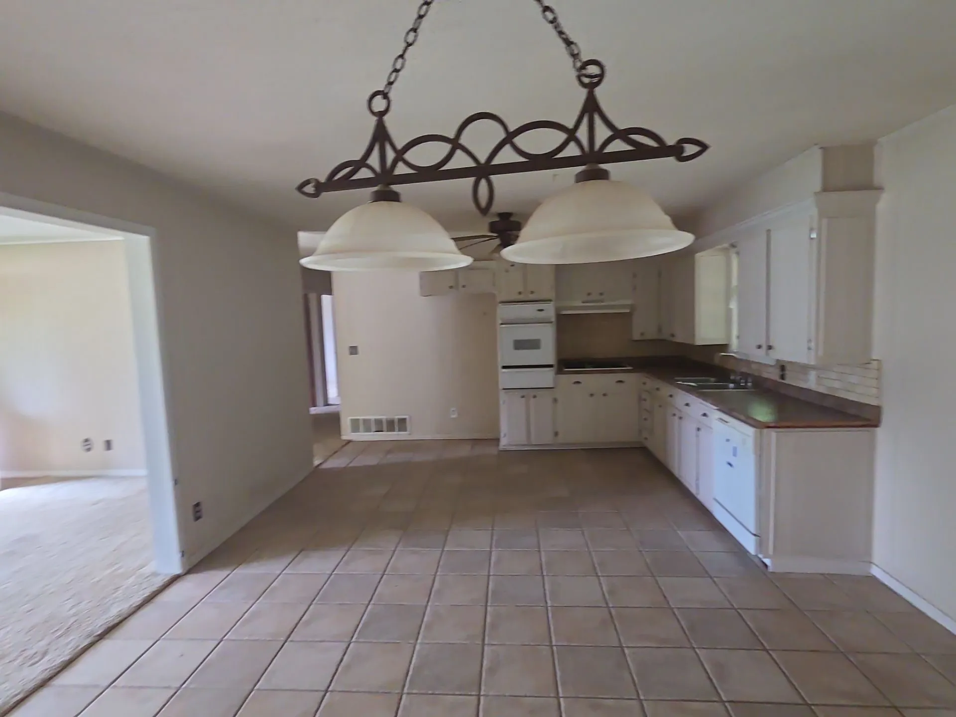 Kitchen featuring extensive white cabinetry, tile flooring, built-in oven, and a decorative chandelier