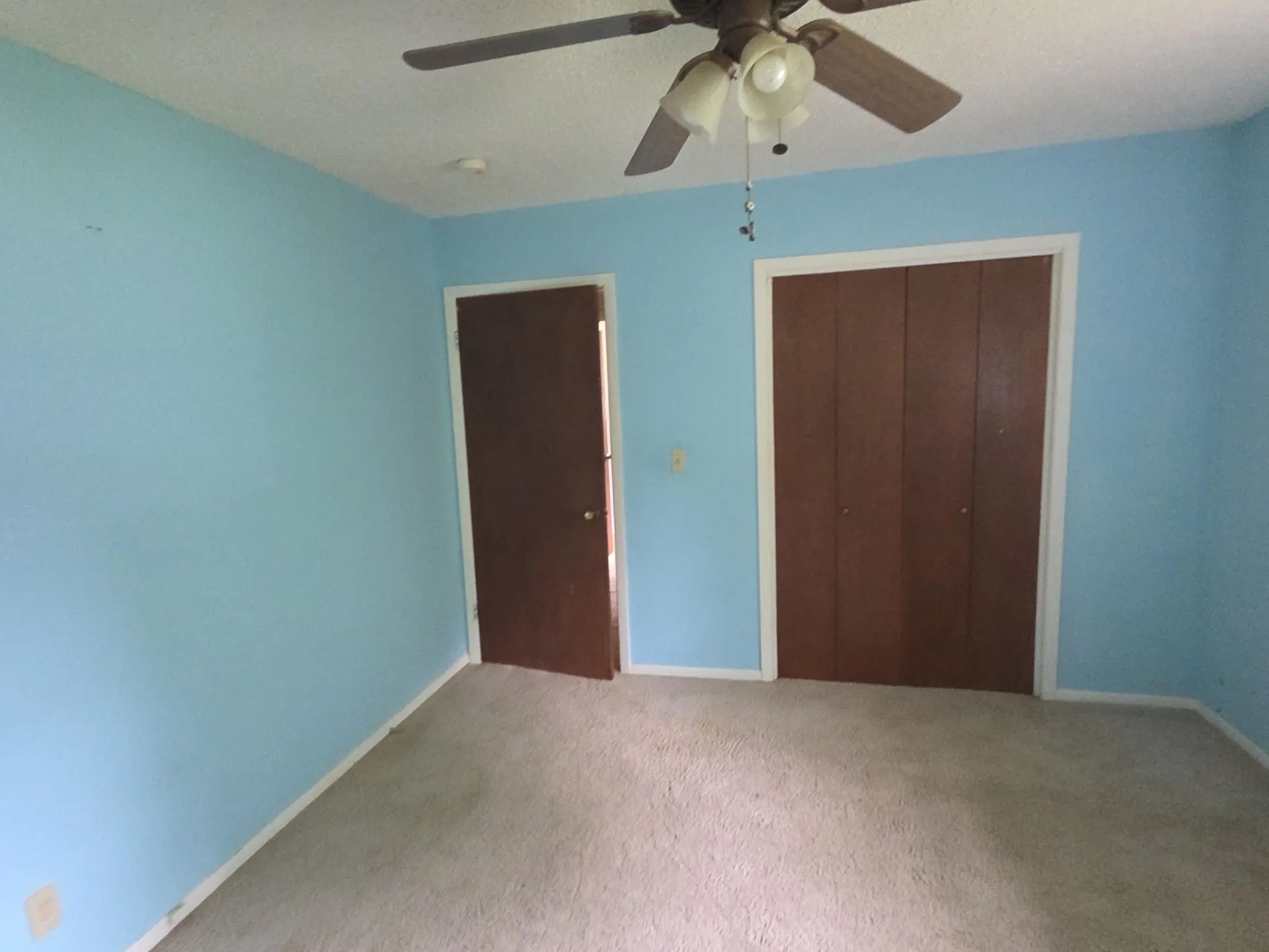 Room featuring light blue walls, a textured ceiling, and neutral carpet flooring