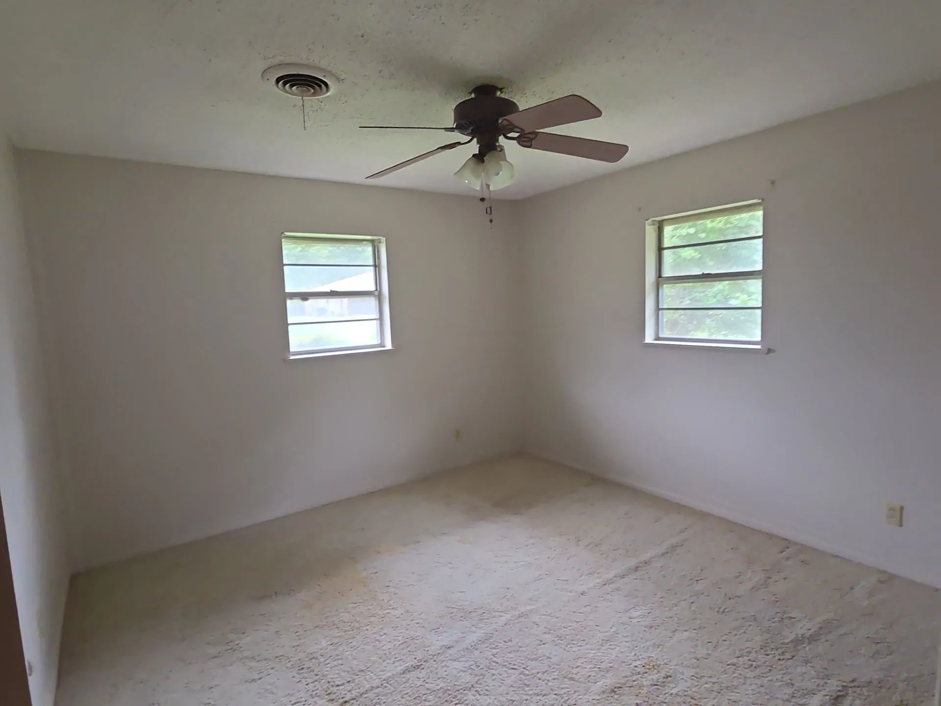 Carpeted room with two windows providing natural illumination