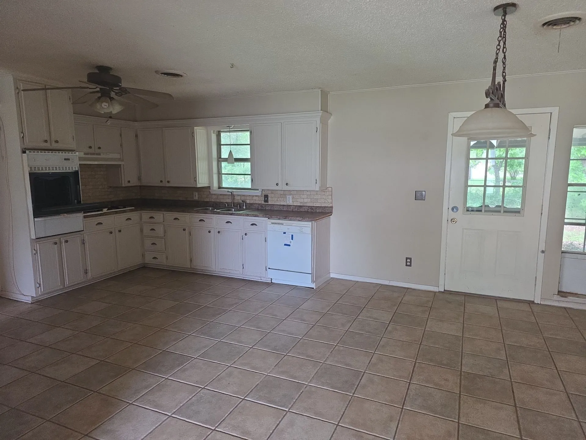 Kitchen featuring white cabinetry, tile flooring, a built-in oven, and a tiled backsplash