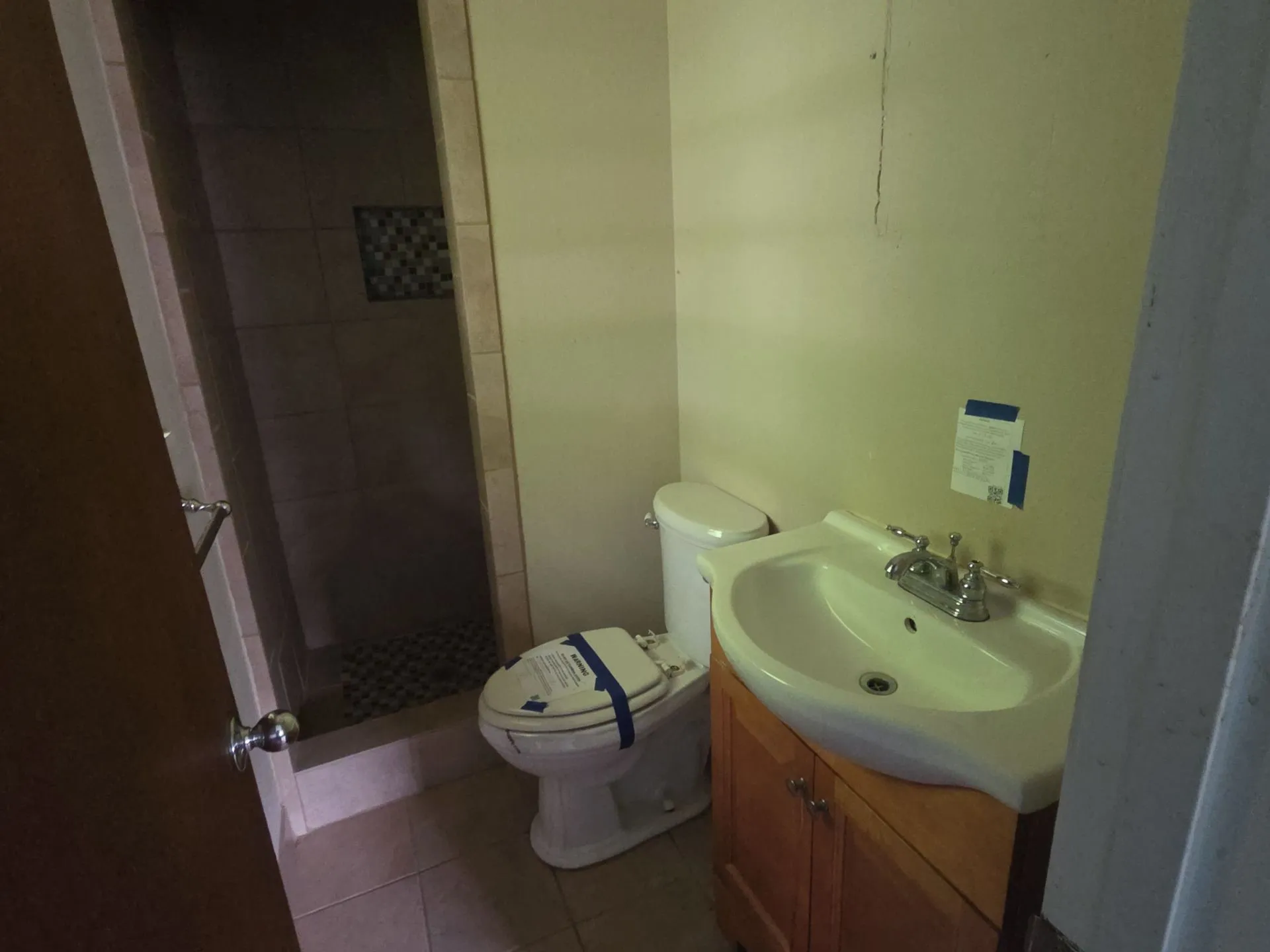 Full bathroom featuring a walk-in shower with tile surround, a mosaic tile accent niche, and a pebble-finish shower floor