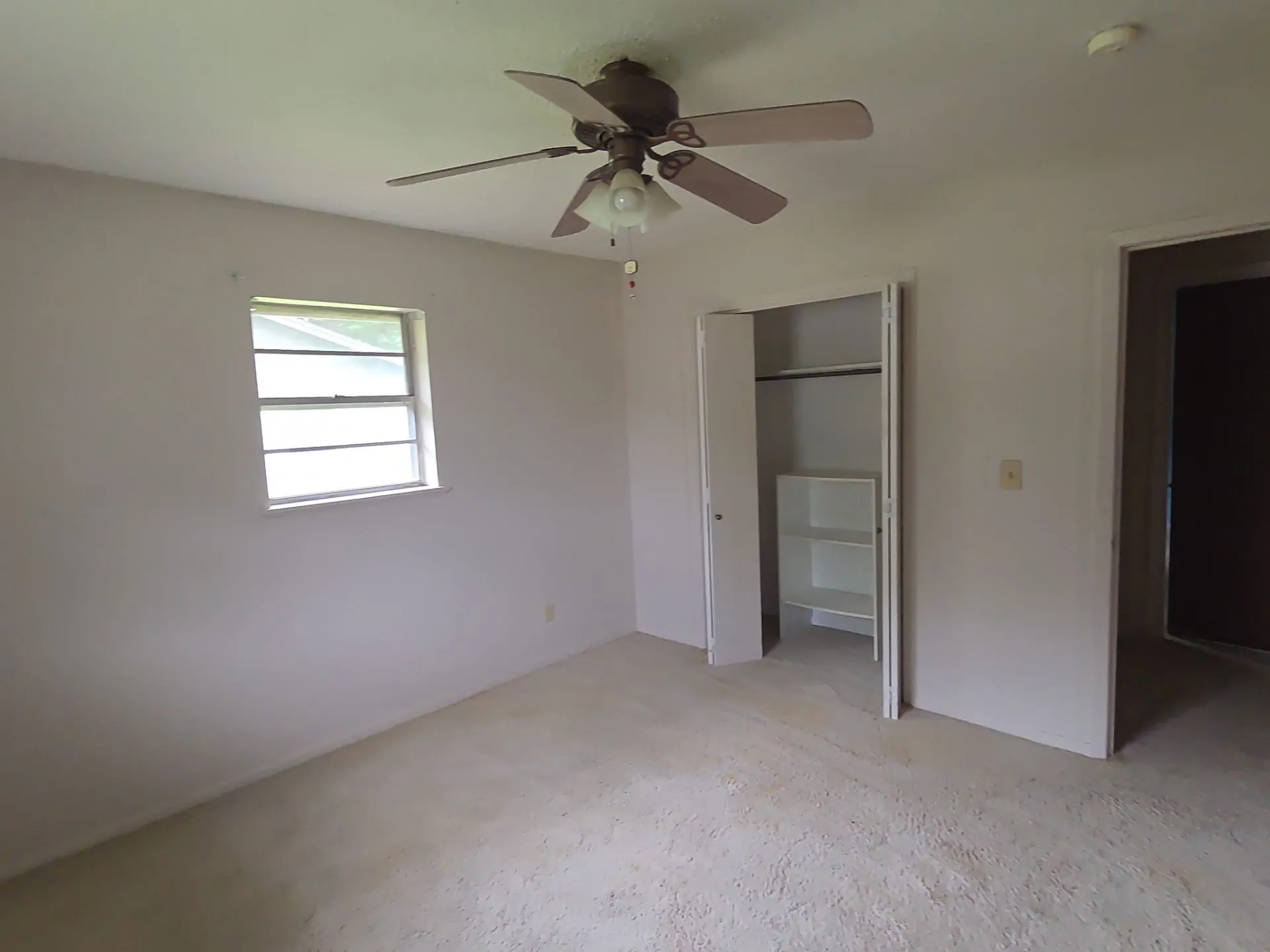 Interior room featuring a ceiling fan with integrated lighting, a window with exterior views, and a closet with bifold doors and built-in shelving