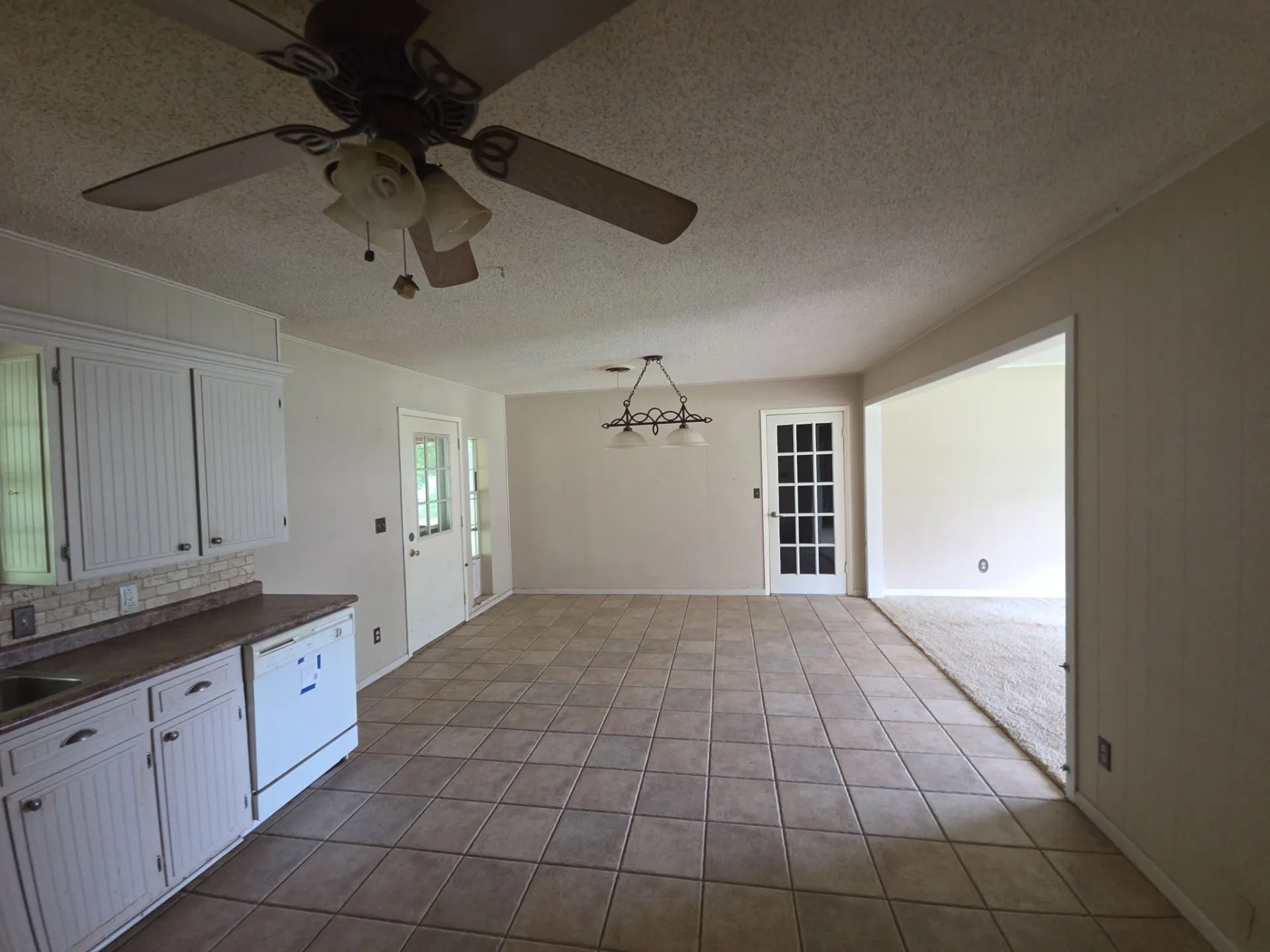Kitchen area featuring white beadboard cabinetry, a mosaic tile backsplash, and a built-in dishwasher