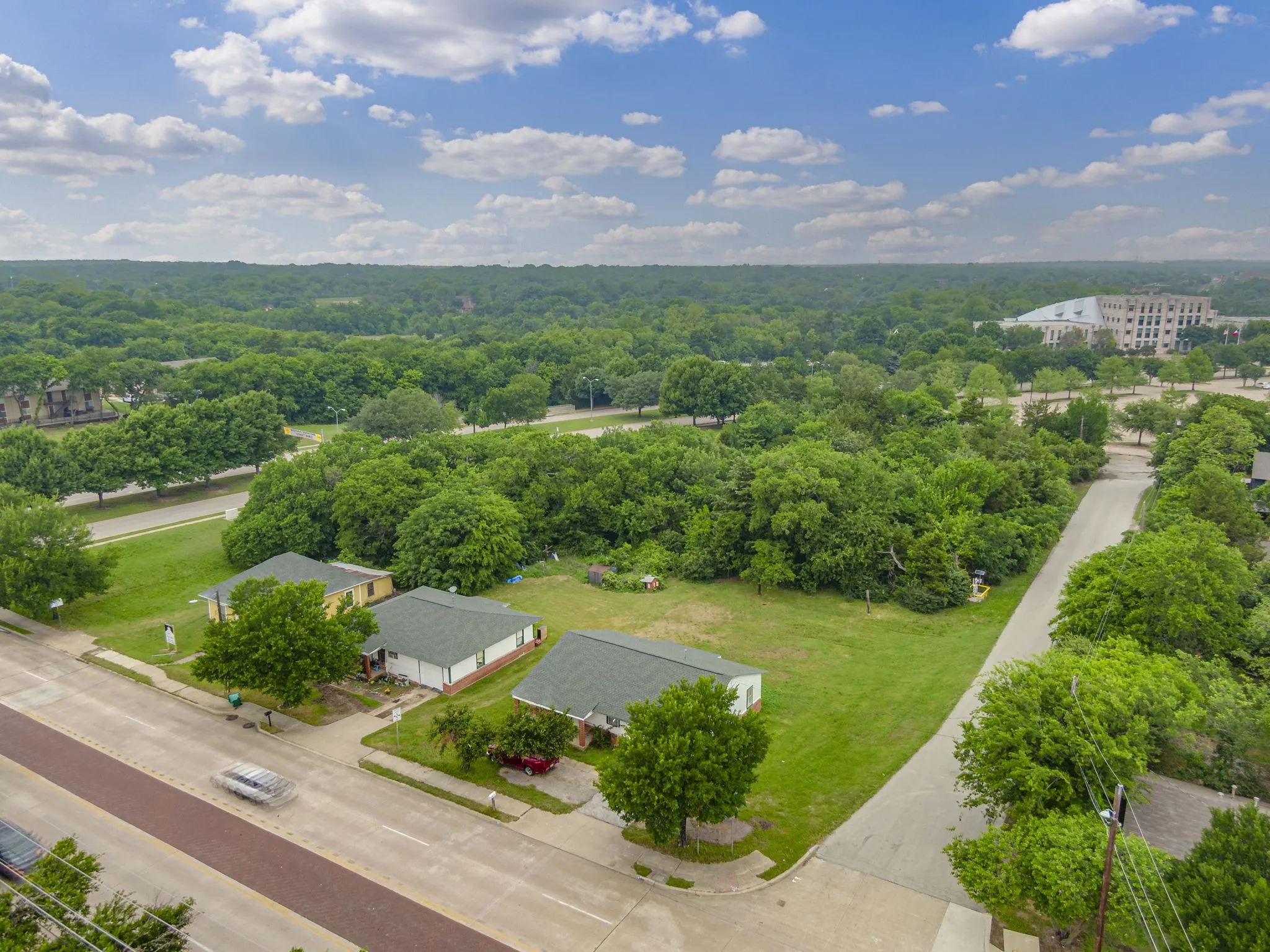 Expansive parcel featuring a large grassy lot, multiple mature trees, and direct street access