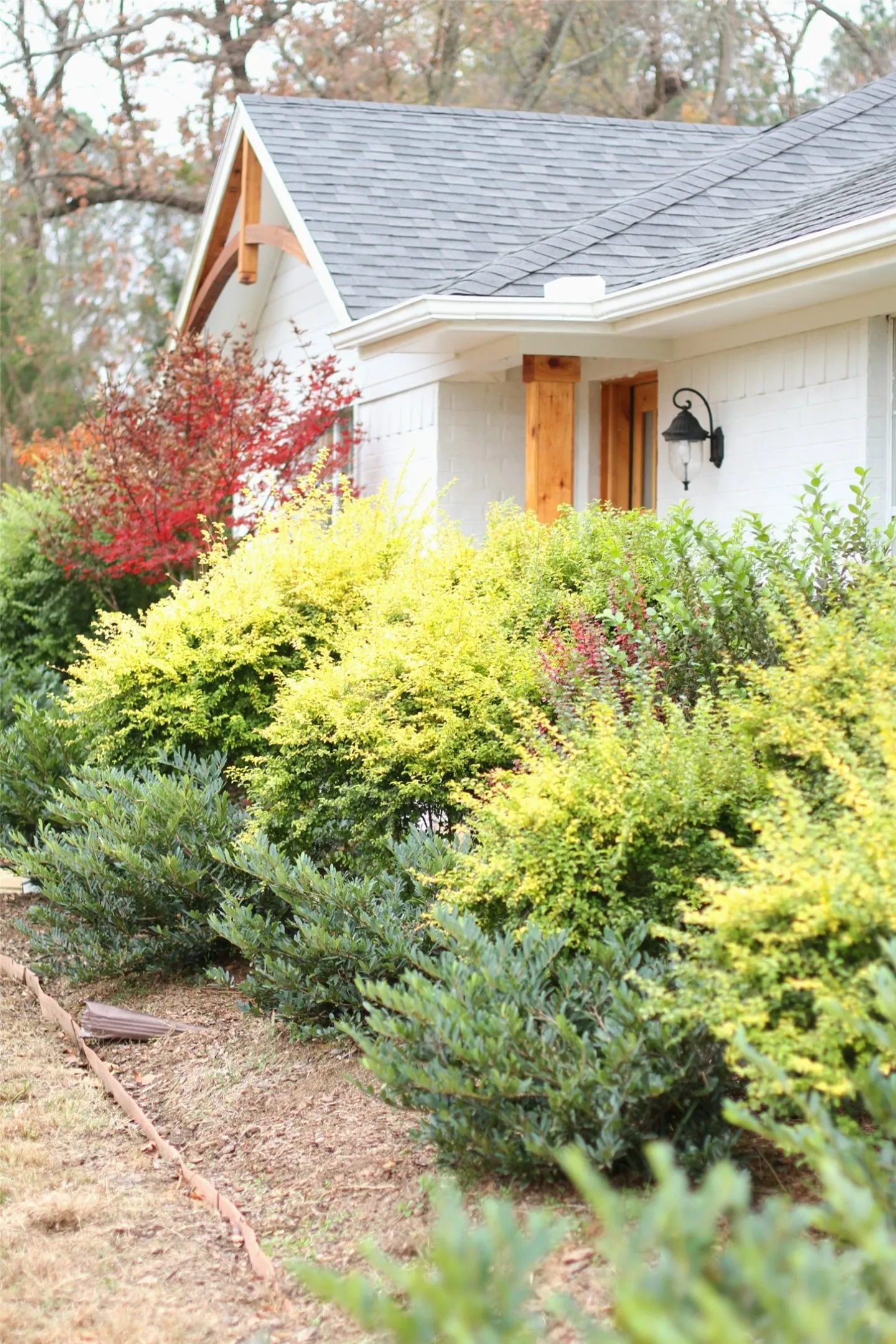 White siding exterior featuring a natural wood beam support and a charcoal shingle roof
