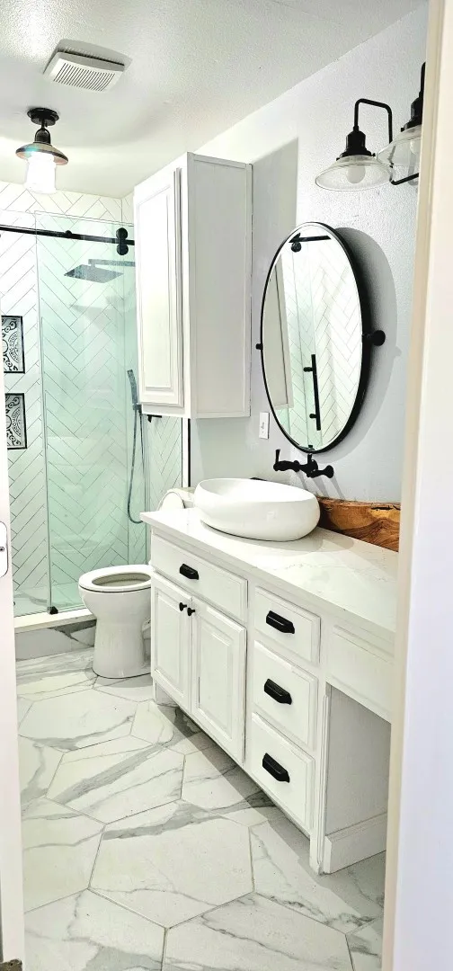 Bathroom featuring a white vanity with black hardware, a vessel sink, and a wall-mounted faucet