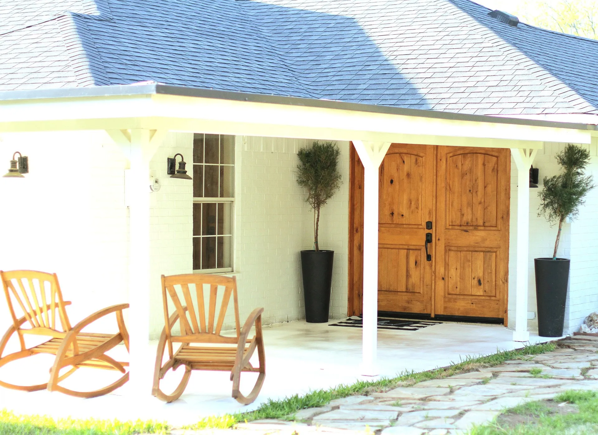 White brick exterior featuring a covered porch with a light-colored concrete surface