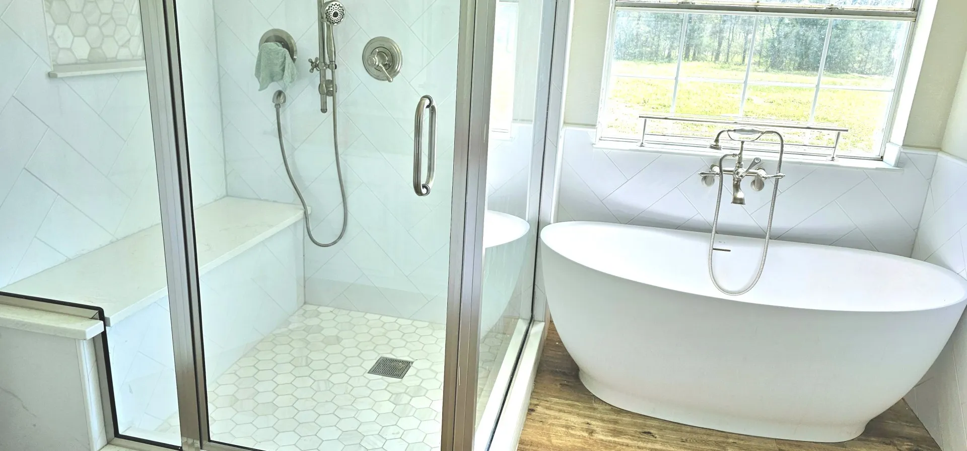 Contemporary bathroom featuring a freestanding soaking tub with floor-mounted faucet, a glass-enclosed shower with a built-in bench, and white subway tile with a decorative accent band