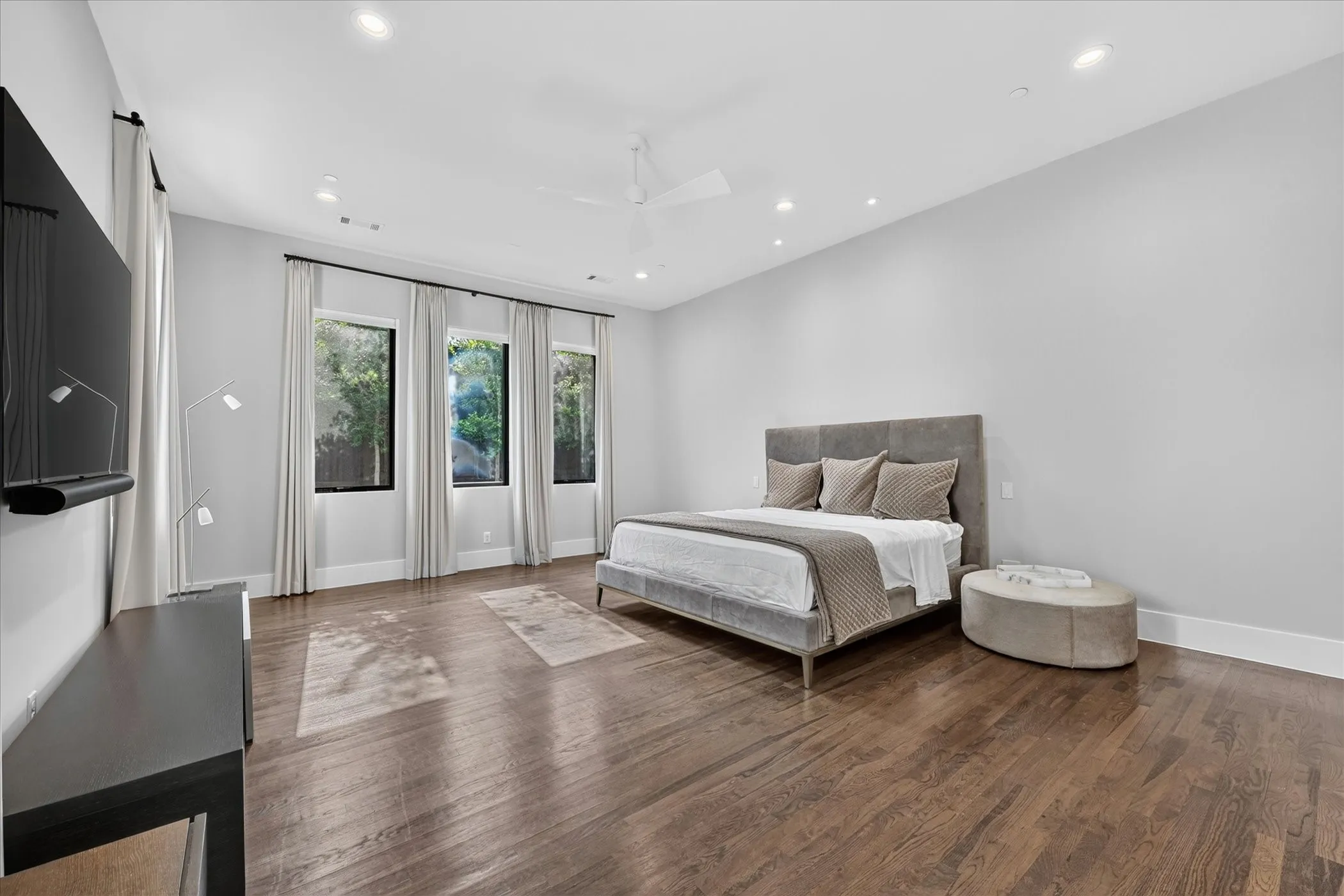 Spacious room with dark wood-finish flooring, light grey walls, and recessed lighting