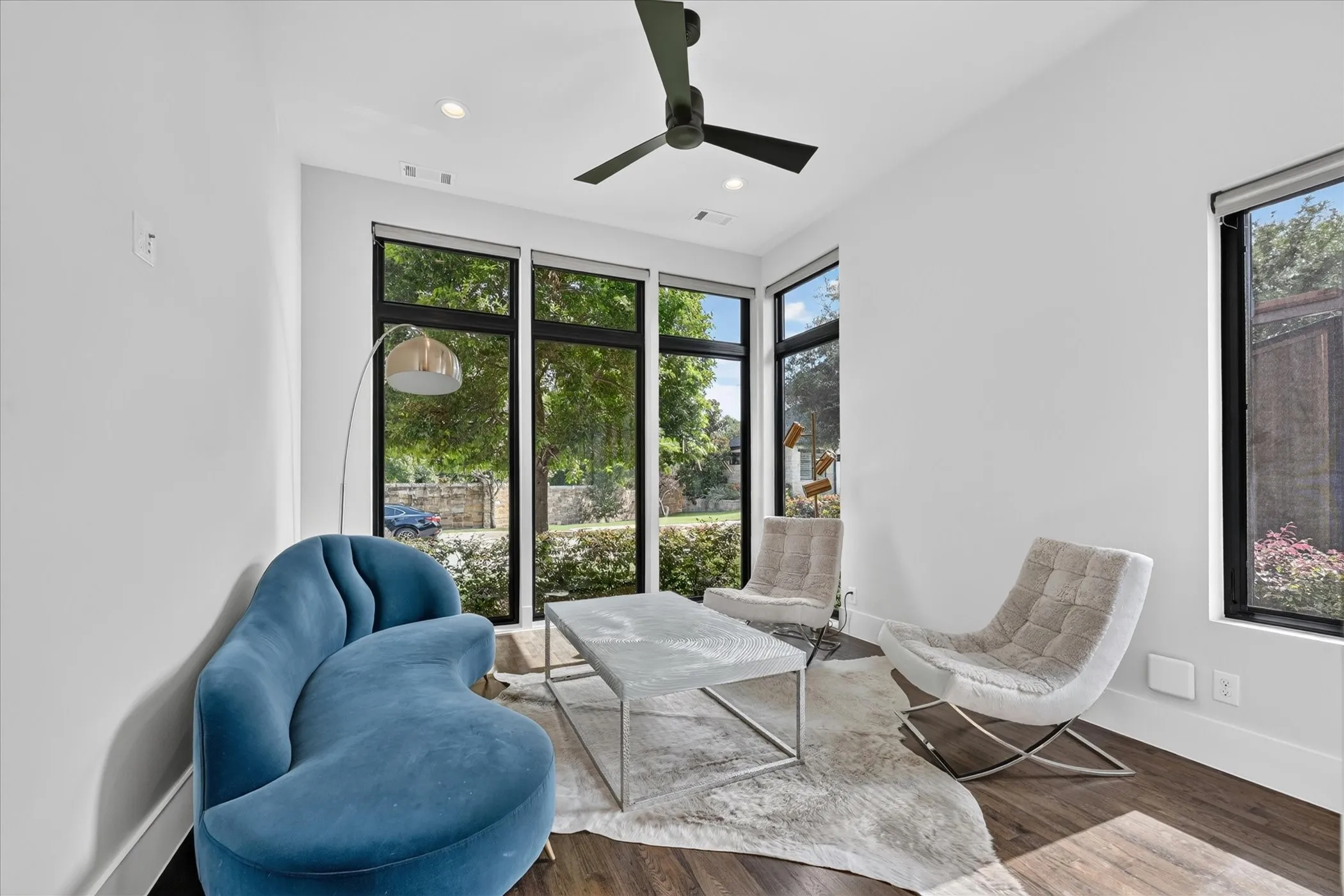 Room featuring dark wood-finish flooring, white walls, and a contemporary ceiling fan with integrated lighting