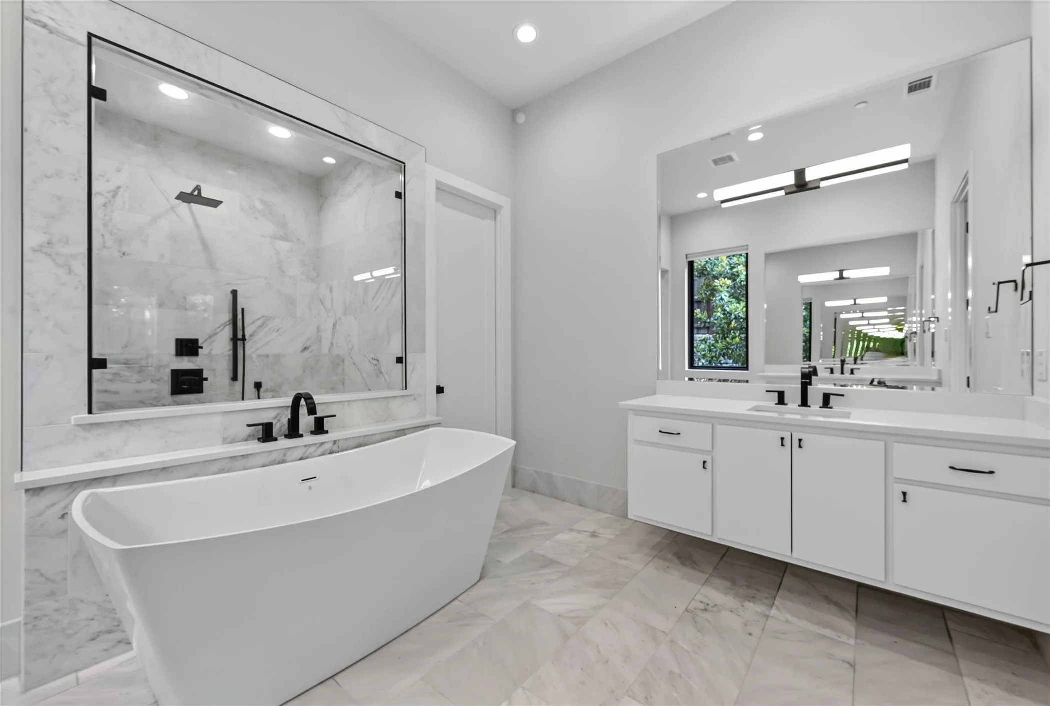 Spacious bathroom featuring a freestanding tub, glass-enclosed shower with multiple fixtures, dual vanity with undermount sinks, and large wall mirrors