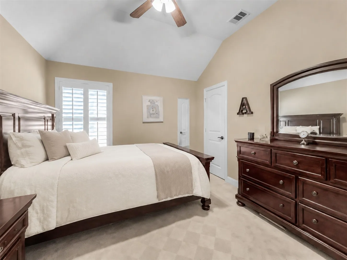 Bedroom 1, Vaulted ceiling with a wood-finish ceiling fan, plantation shutters, and light-colored carpeting