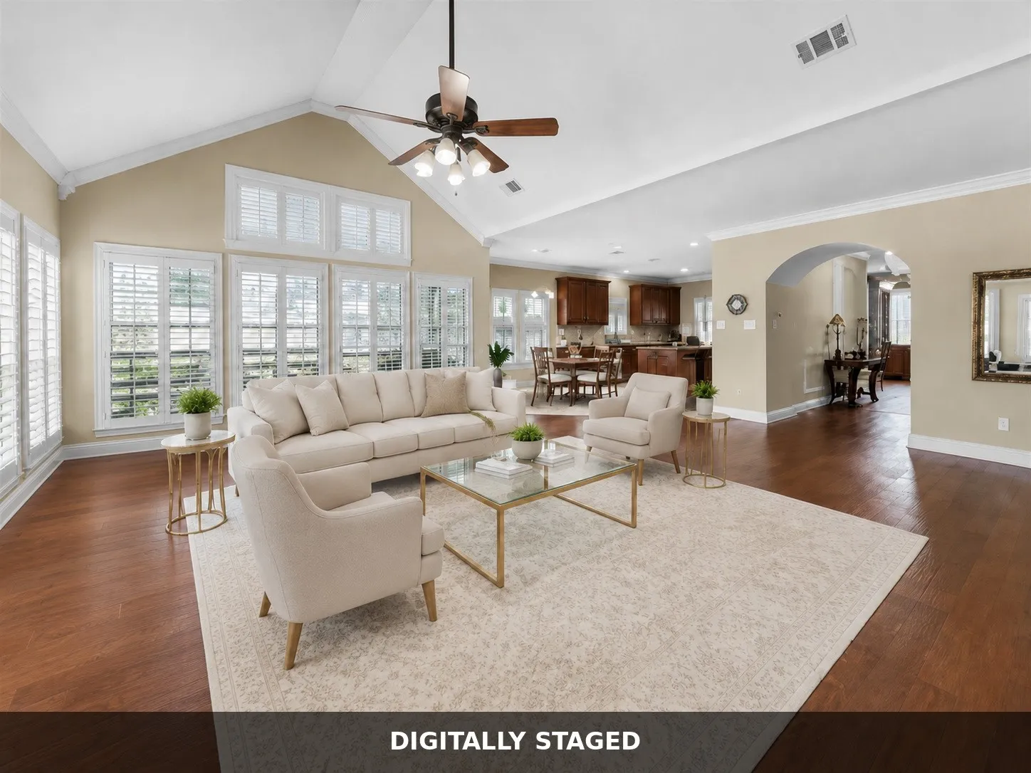 Vaulted ceiling with a ceiling fan, multiple windows with plantation shutters, wood-finish flooring, and an arched entryway