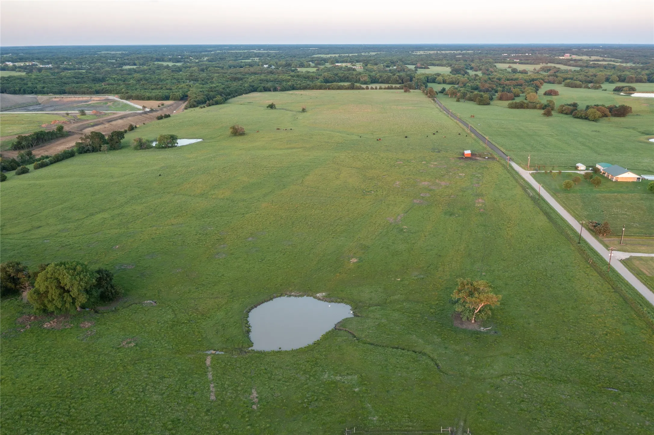 Expansive green acreage featuring a serene pond
