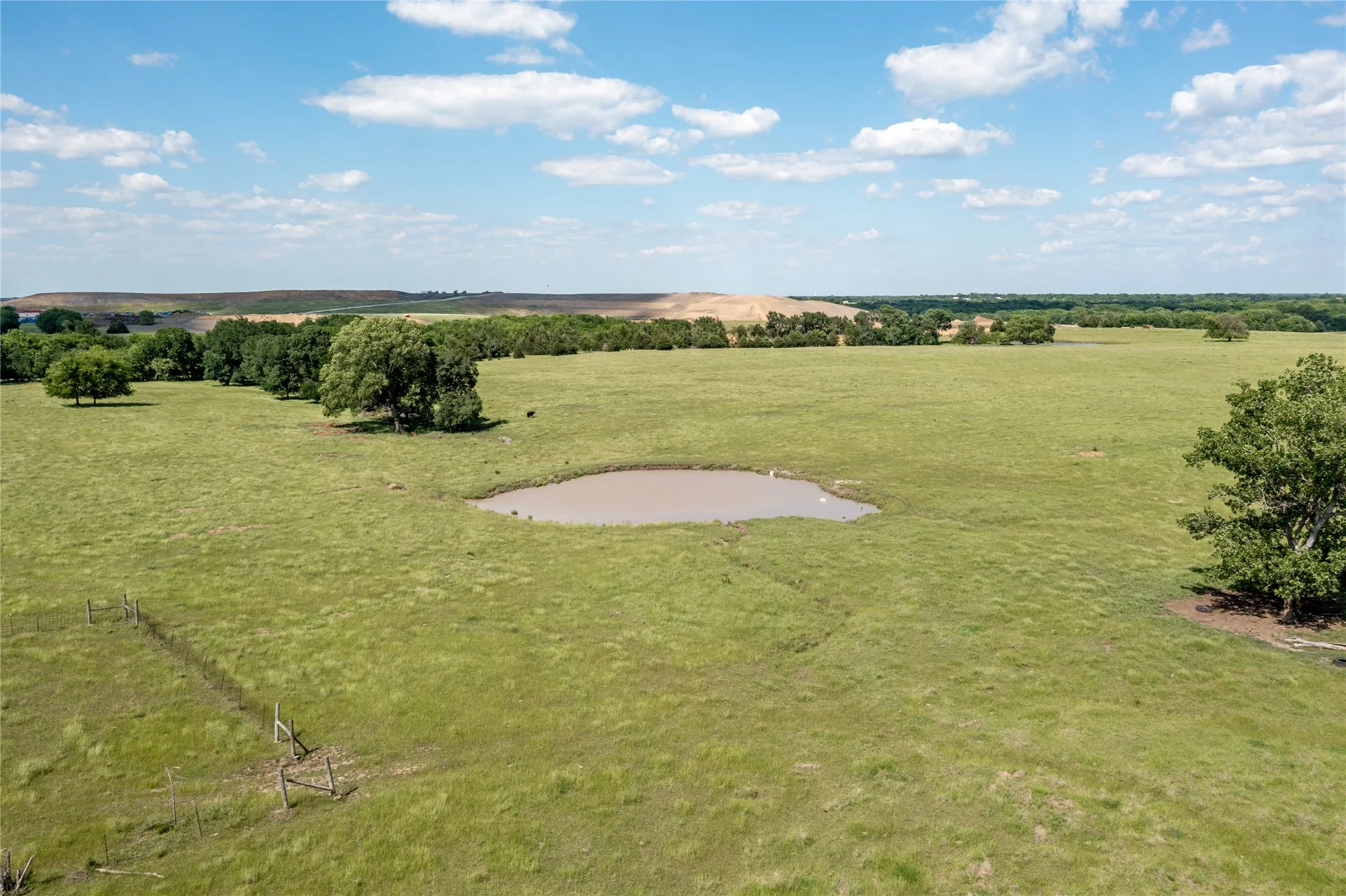 Expansive green pastureland with a central pond feature