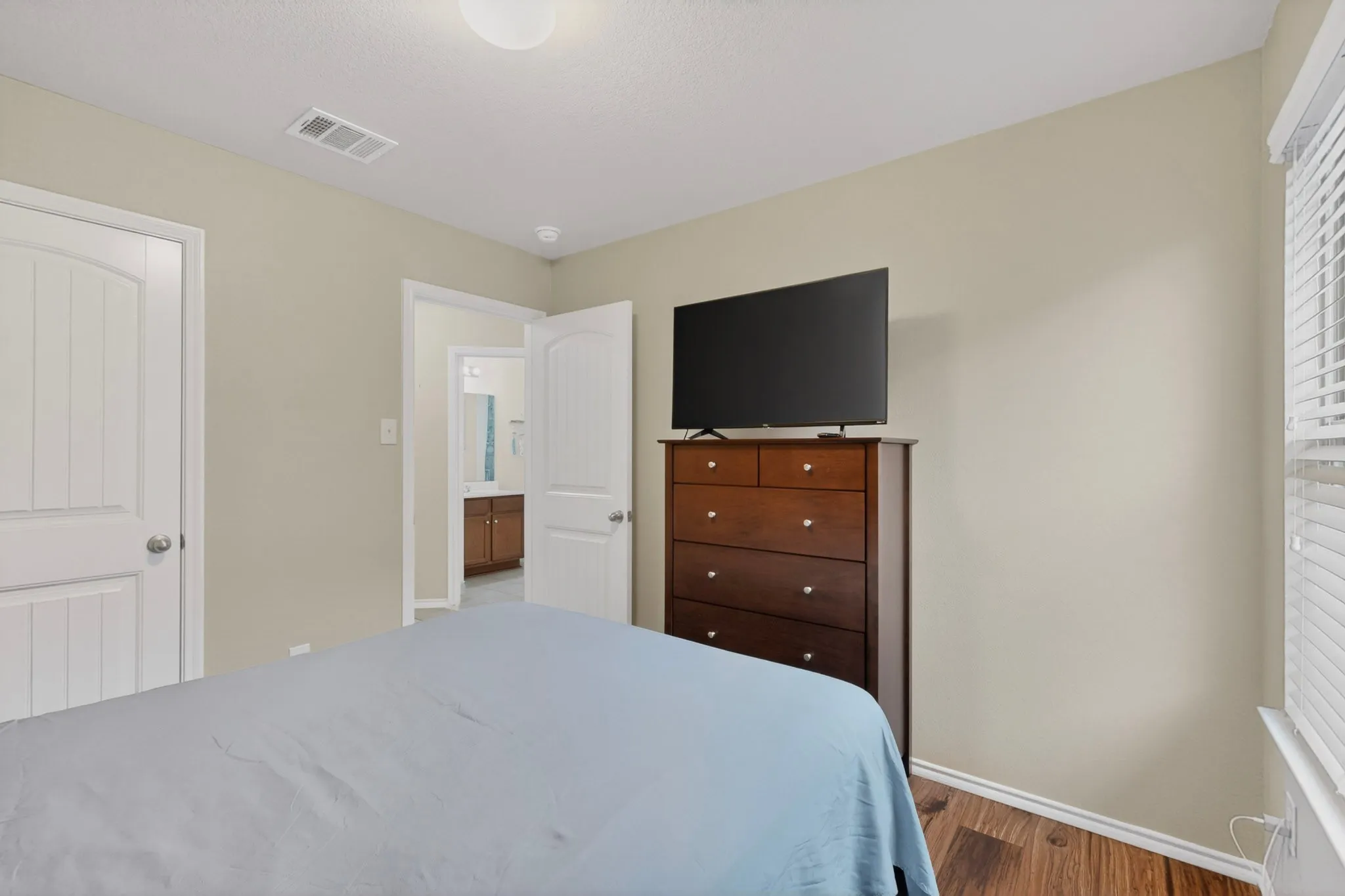 Interior space featuring wood-finish flooring, light-toned walls, white trim, and a window with blinds