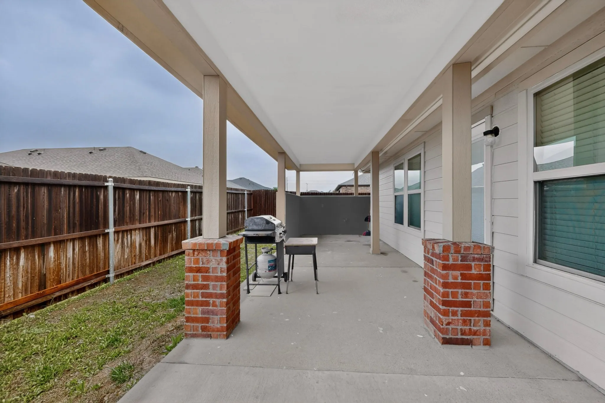 Covered patio featuring concrete flooring and brick-clad support columns