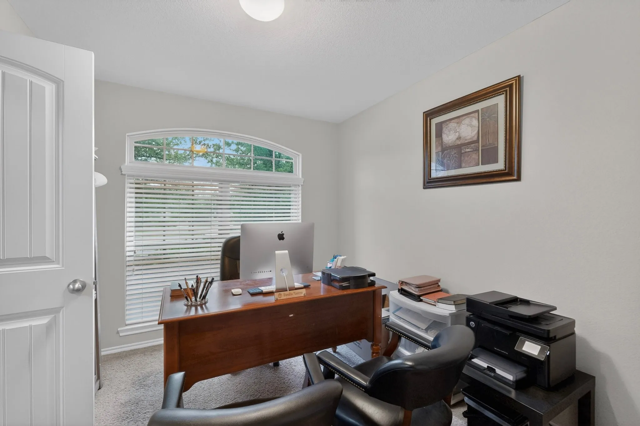 Room featuring a large arched window with blinds, light gray walls, and carpet flooring