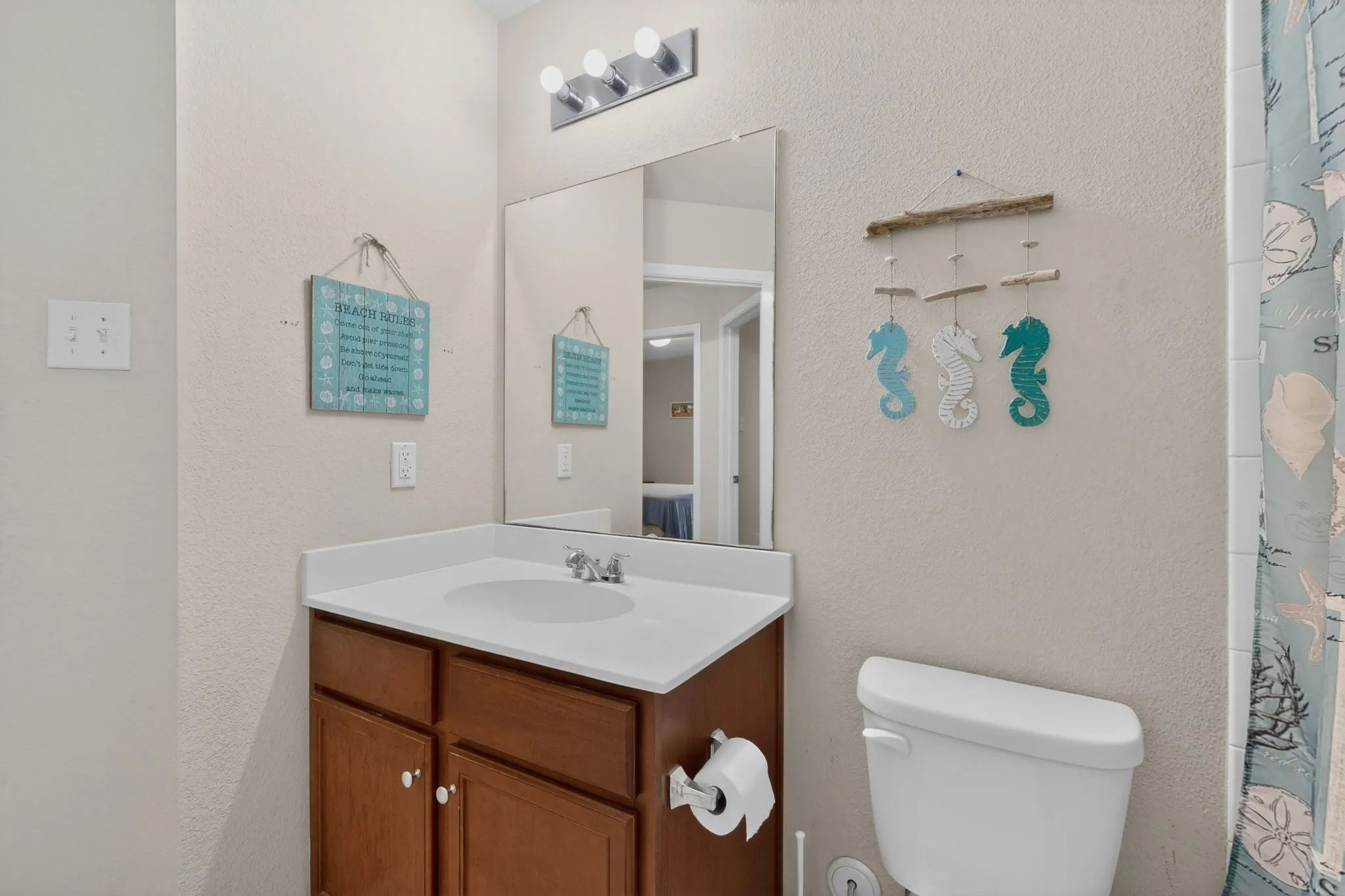 Bathroom featuring a vanity with a wood-finish cabinet, white countertop with integrated sink, and an overhead light fixture