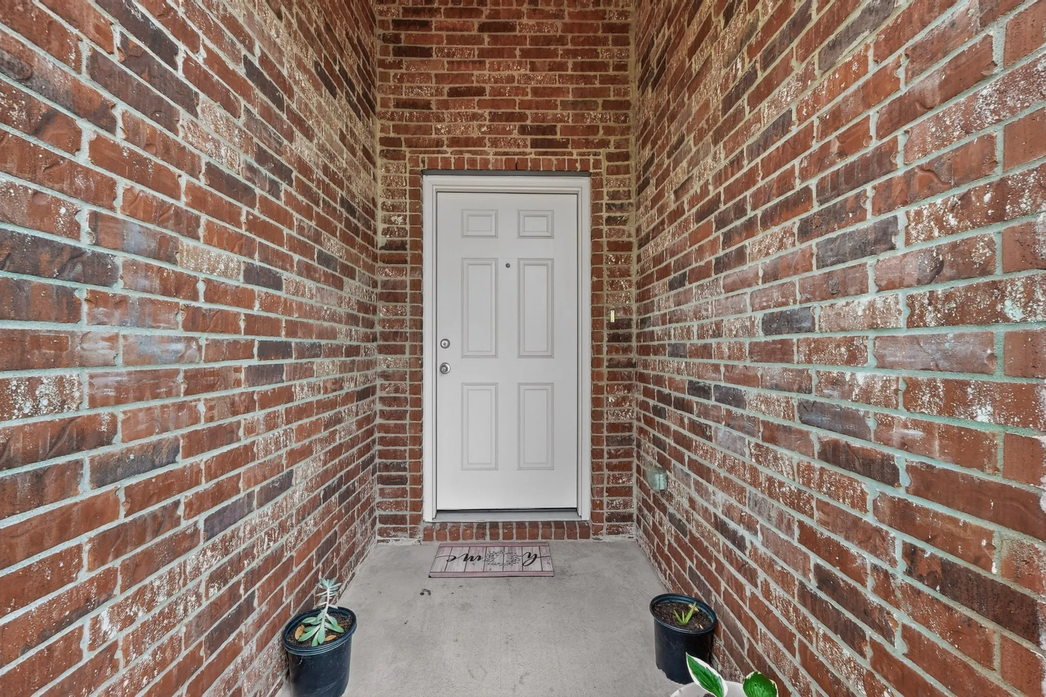 Recessed entryway featuring multi-toned brickwork and a paneled white door