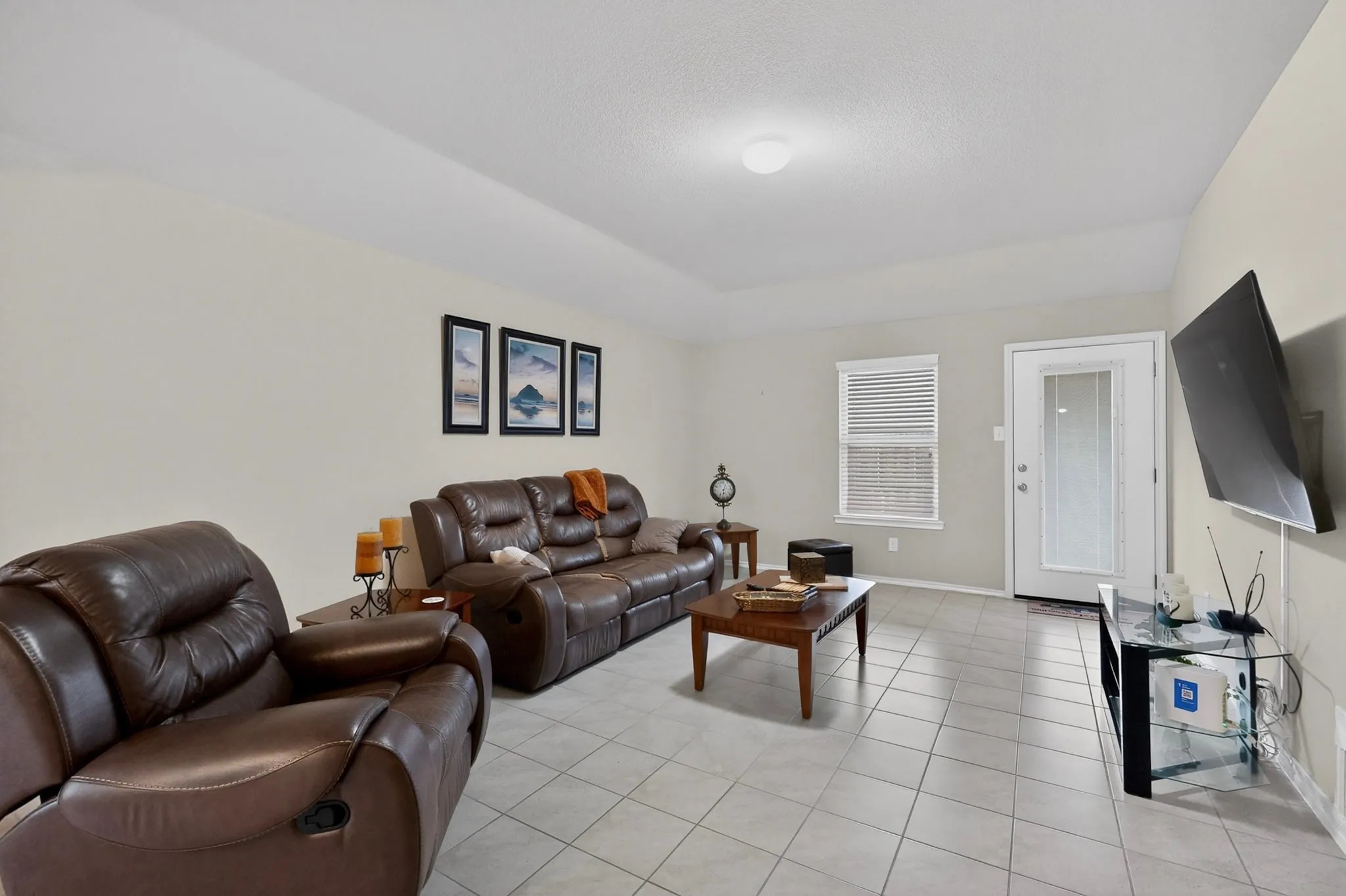 Spacious living area featuring light-toned tile flooring, neutral wall tones, and a white ceiling