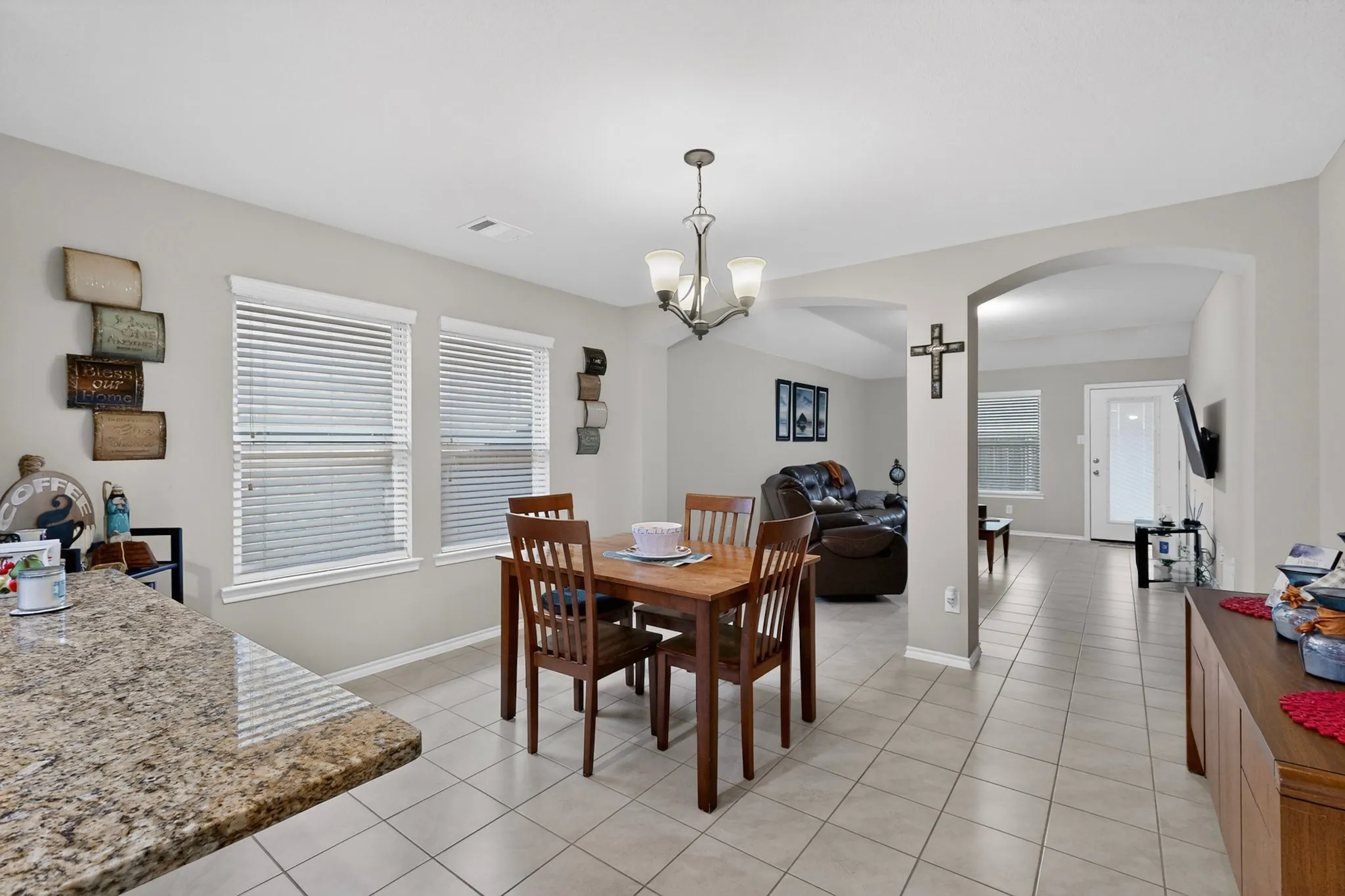 Dining area featuring tile flooring, a chandelier light fixture, and two windows with blinds