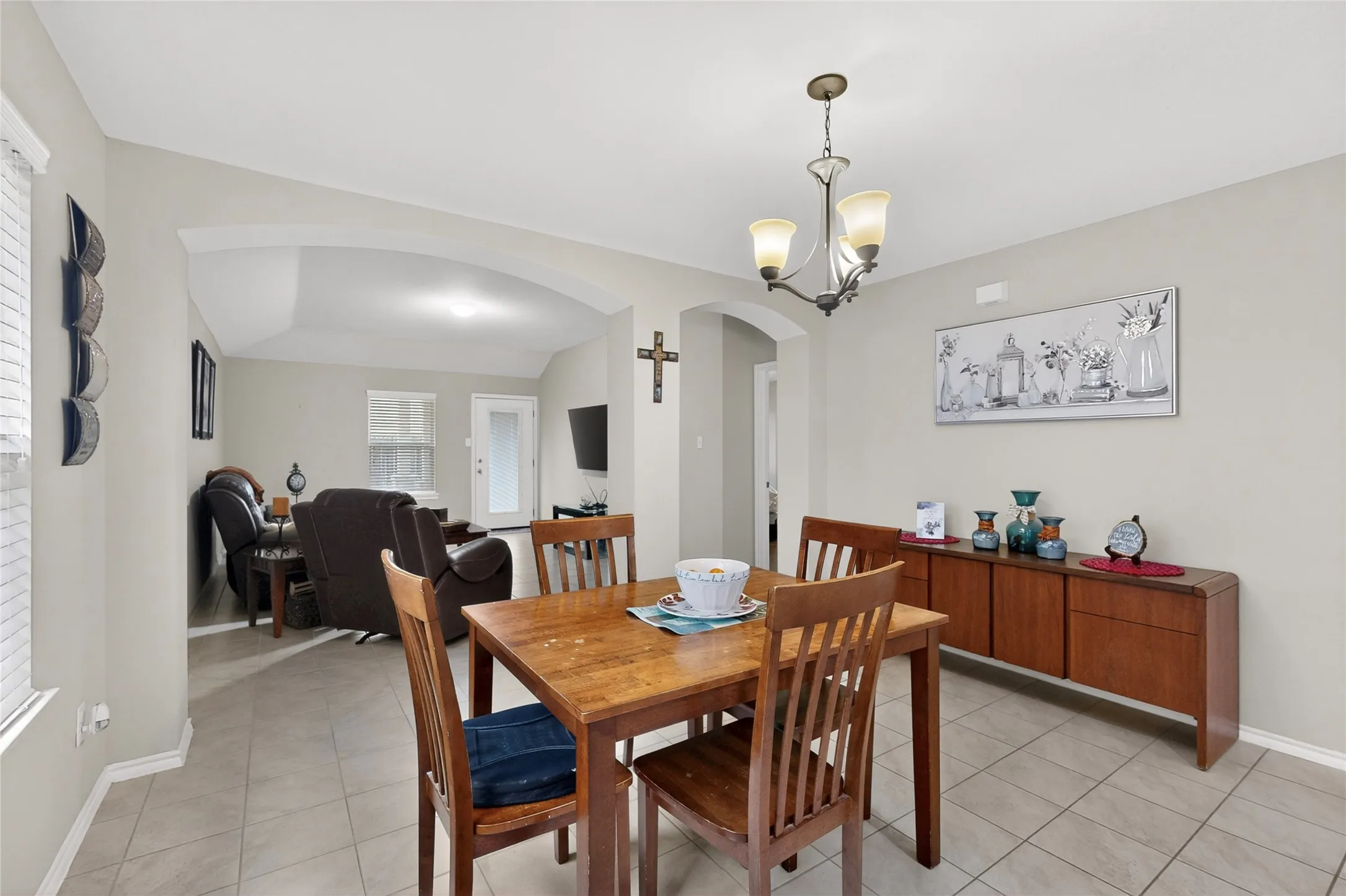Dining area featuring neutral wall tones, tile flooring, and an archway opening to a separate living space