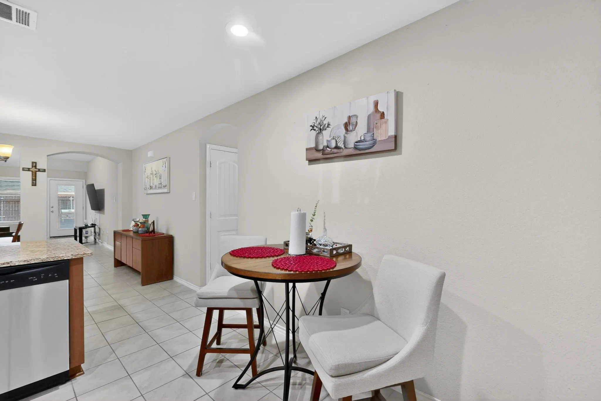 Kitchen area featuring an integrated dishwasher, granite-finish countertop, and tile flooring