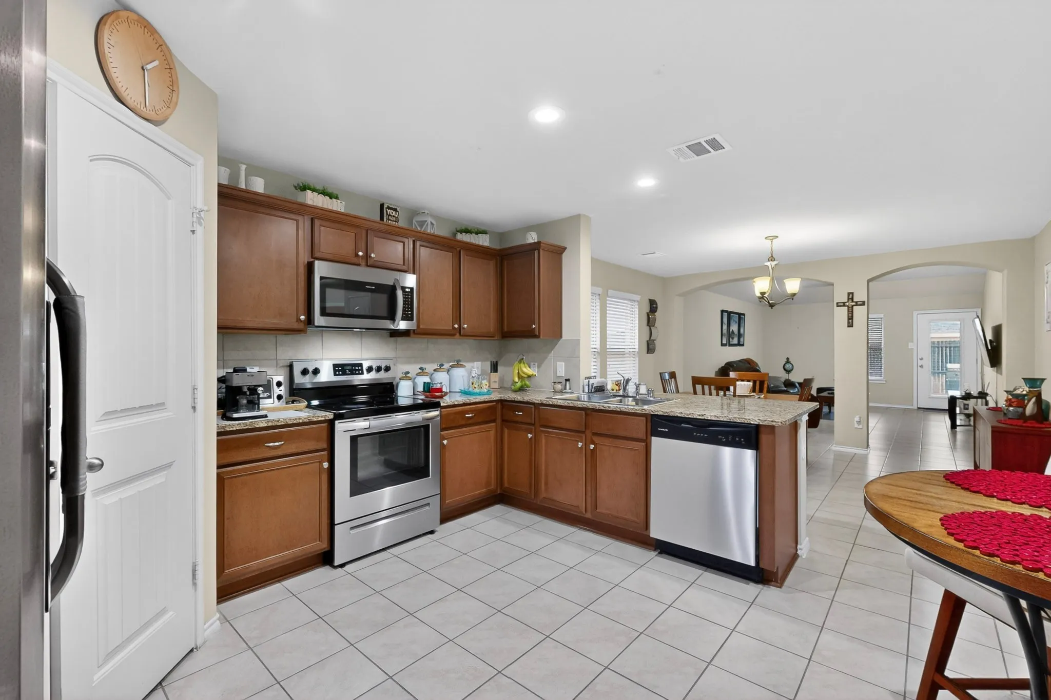 Expansive kitchen featuring wood cabinetry, stainless steel appliances, and light-toned tile flooring