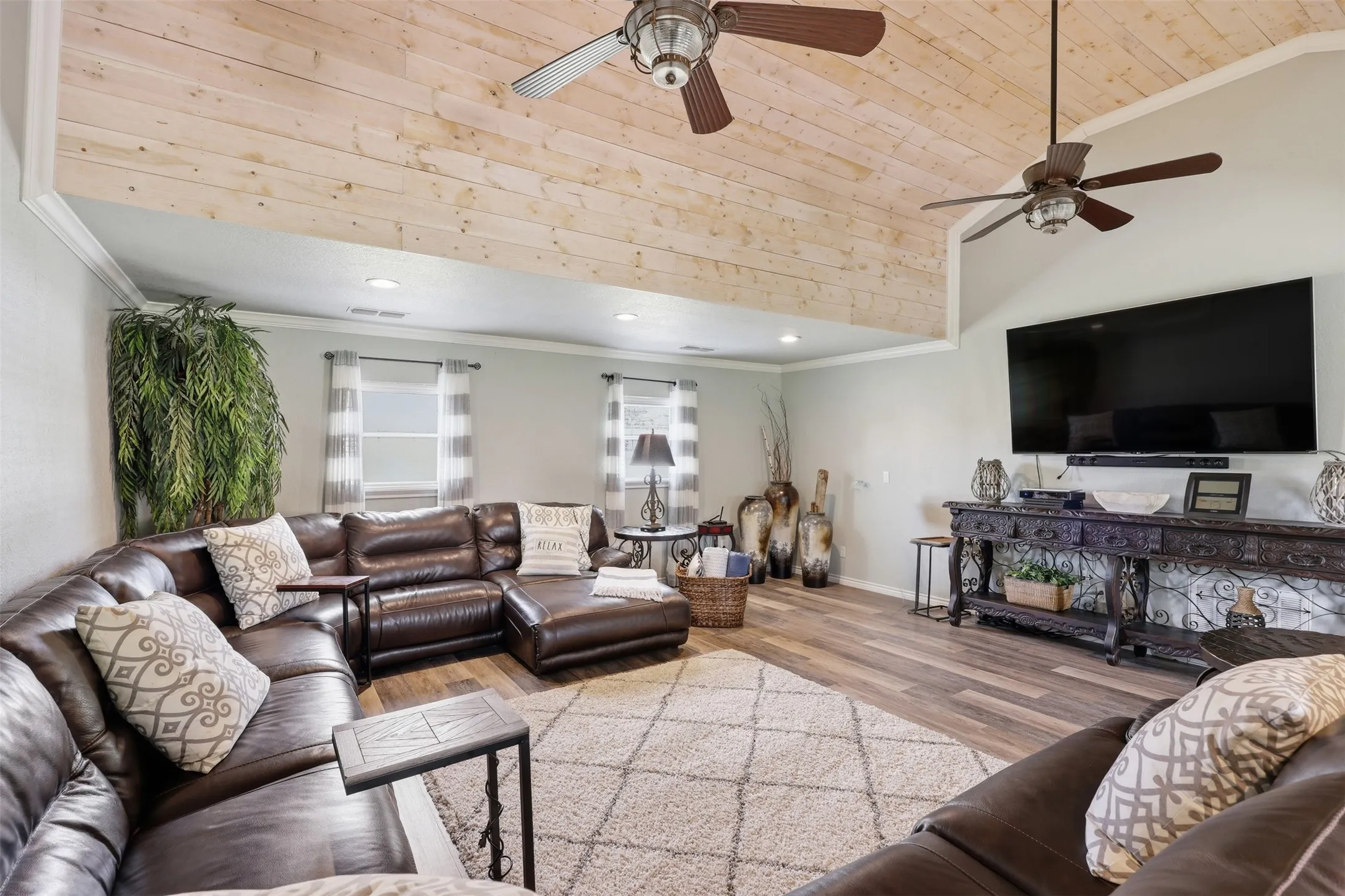 Vaulted ceiling featuring wood-finish paneling and two ceiling fans