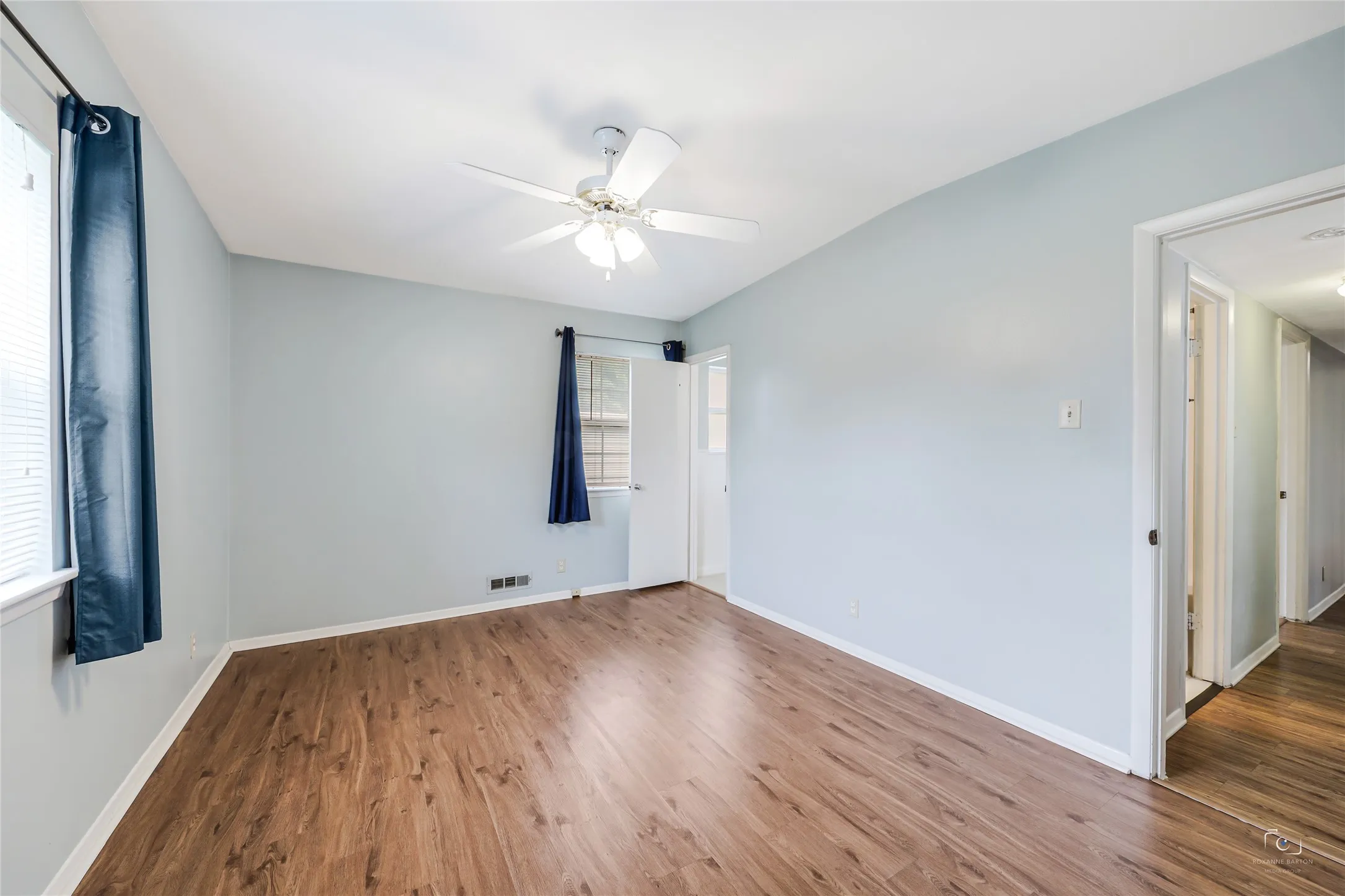 The primary bedroom offers views of the front yard and side yard - natural light and window coverings!  Lighted ceiling fan- no popcorn ceilings and no carpet!  Easy access to other bedrooms and extra full bath and accessory built-in dual hampers- storage - cabinets!