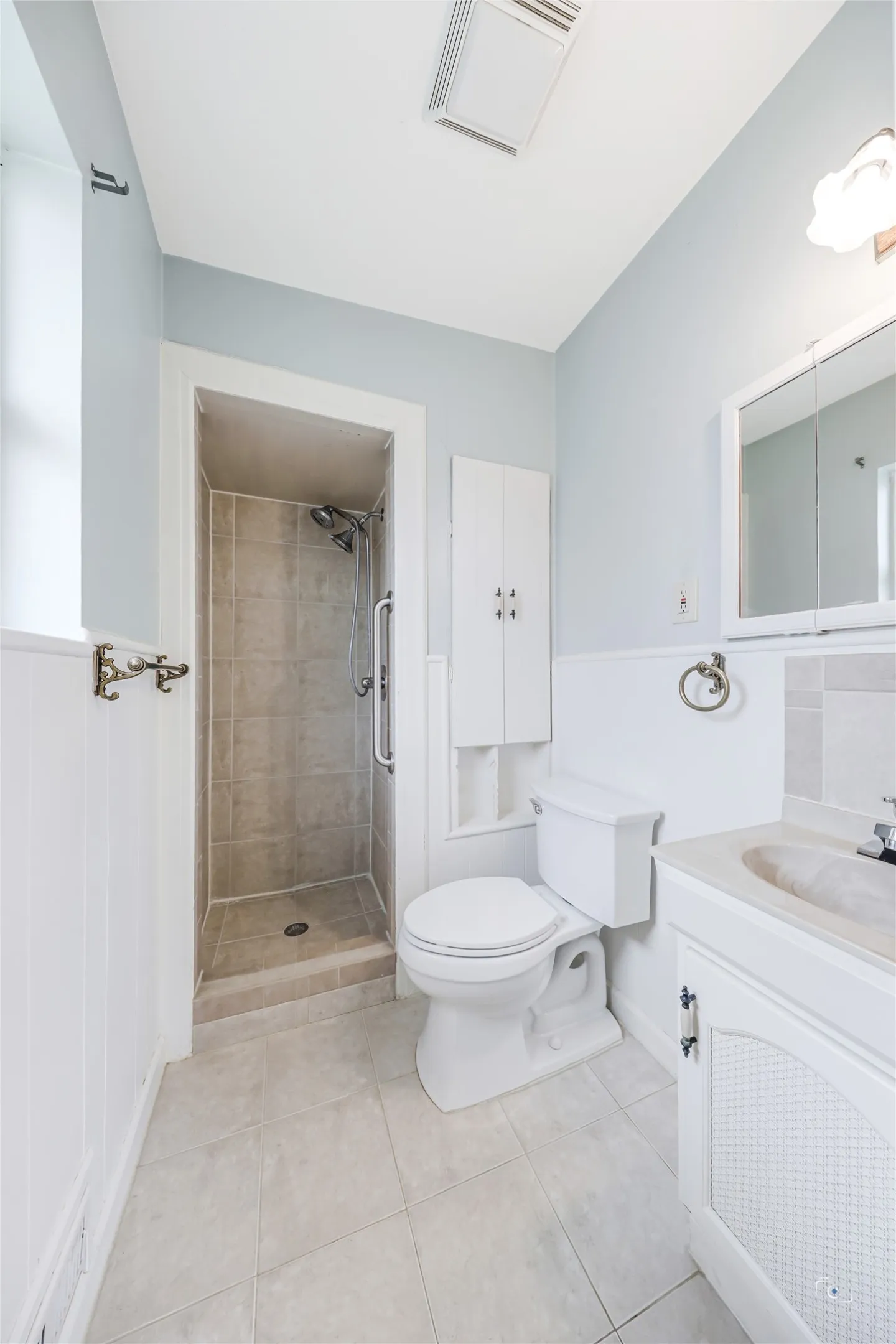 Views of the primary private shower -bath - with frosted window for natural light and privacy, medicine storage and cbuilt-i as well as hardware for towels, hand towel, etc and tile floors!   Free movable body spray as well as fixed shower Head in this tiled shower!
