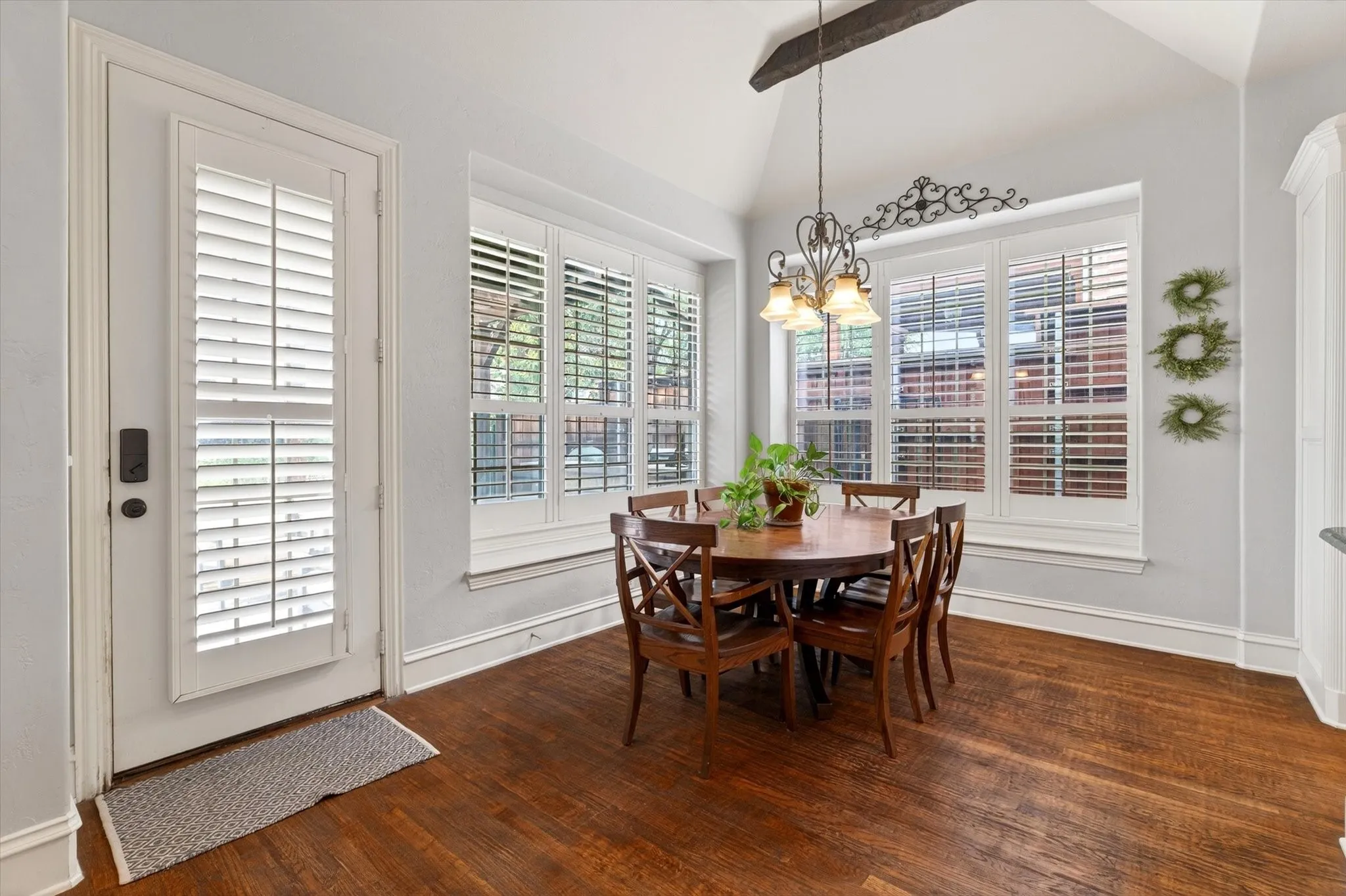 The breakfast area features wood beams, plantation shutters, and charming L-shaped window seating overlooking the backyard.