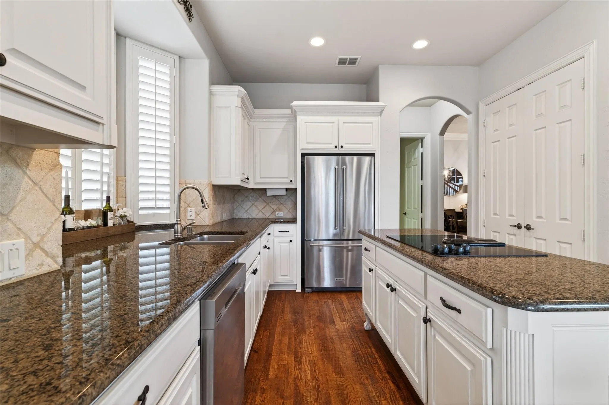 The kitchen delivers everyday function with granite countertops, stainless steel appliances, dual ovens, island seating, and tons of cabinet storage.