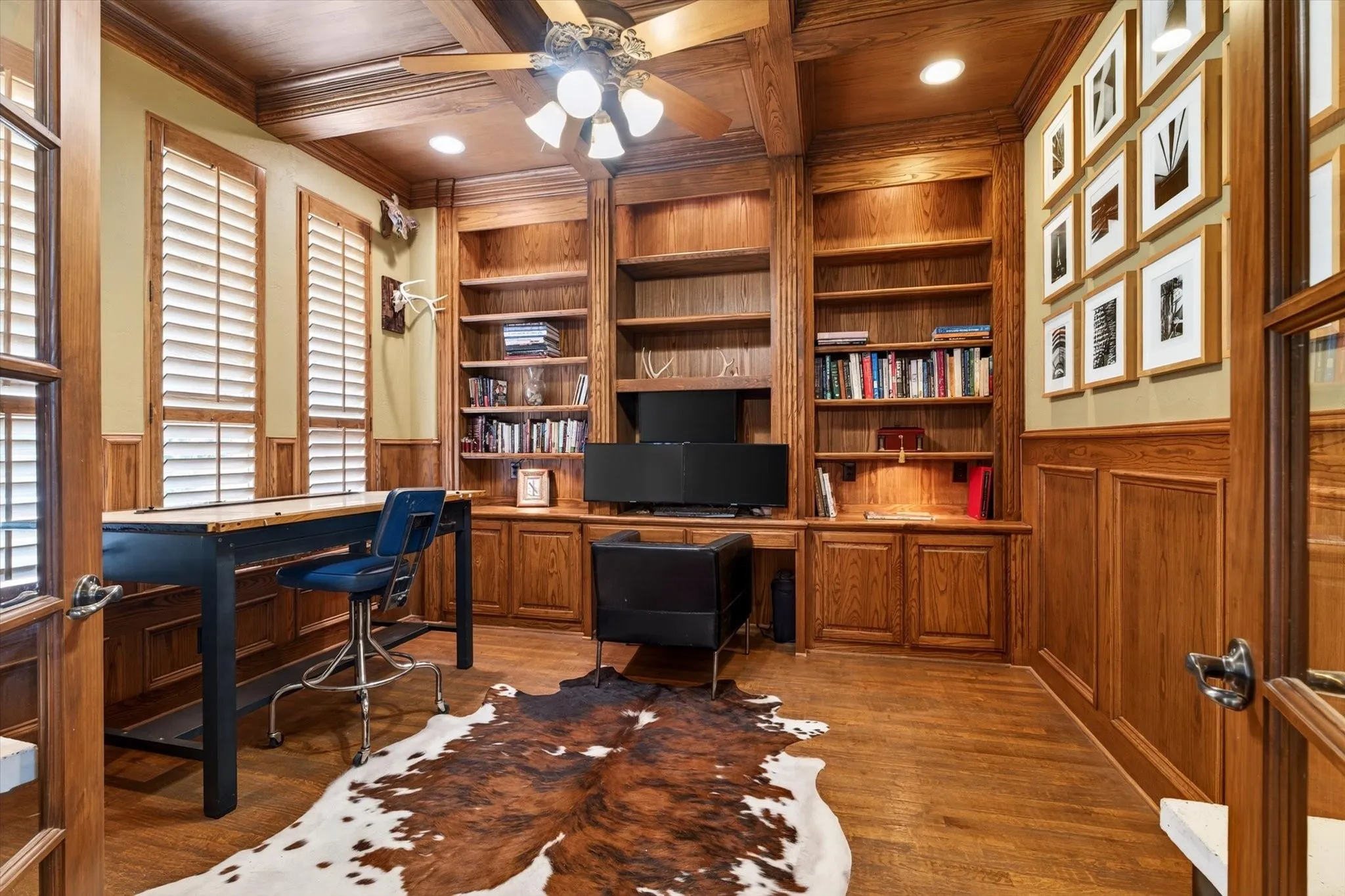 A true study with dual French doors, extensive crown molding, rich built-ins, and coffered ceiling details creates a polished work-from-home space.