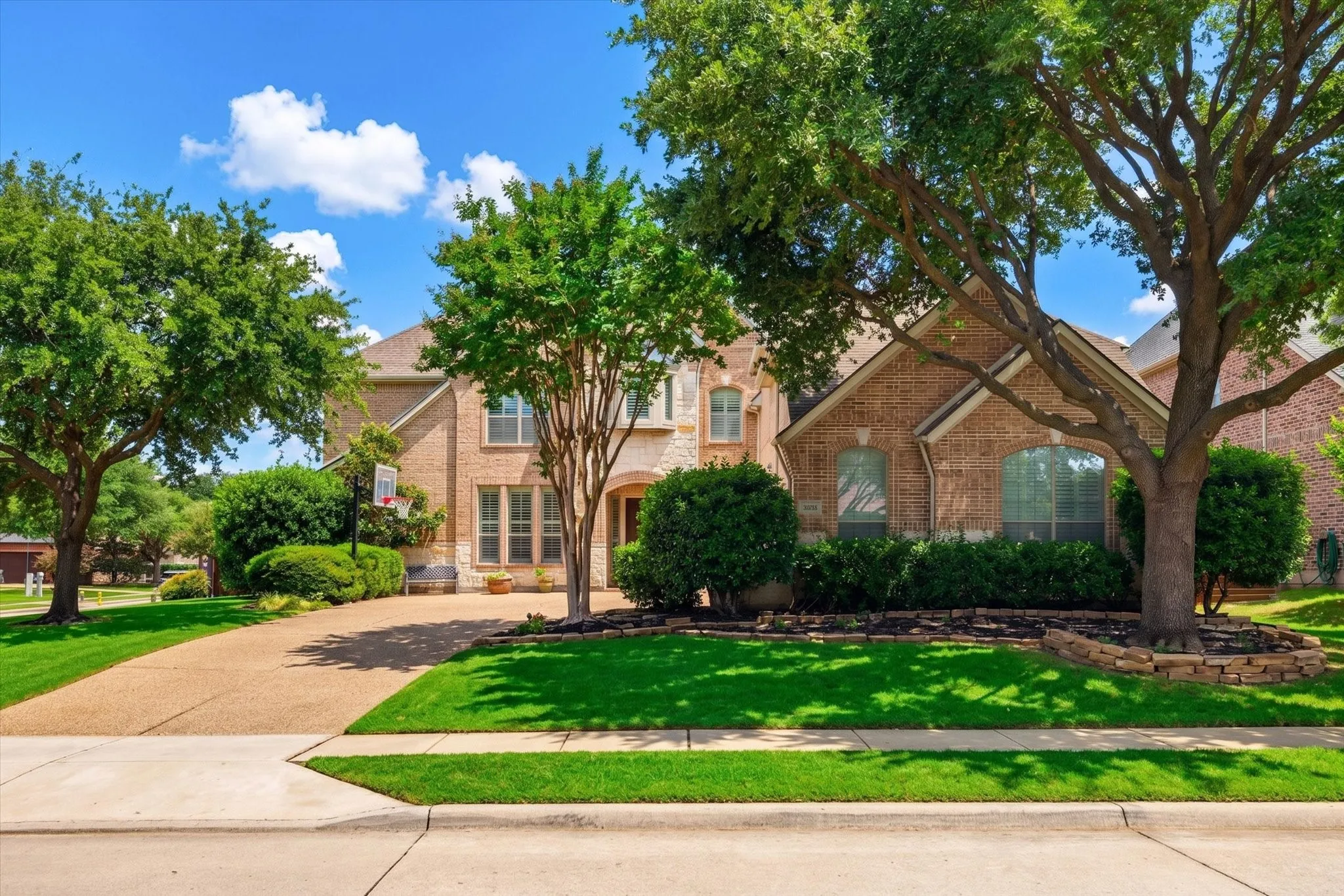 Beautiful curb appeal welcomes you with mature trees, lush landscaping, a wide driveway, and a stately brick elevation in The Trails of West Frisco.