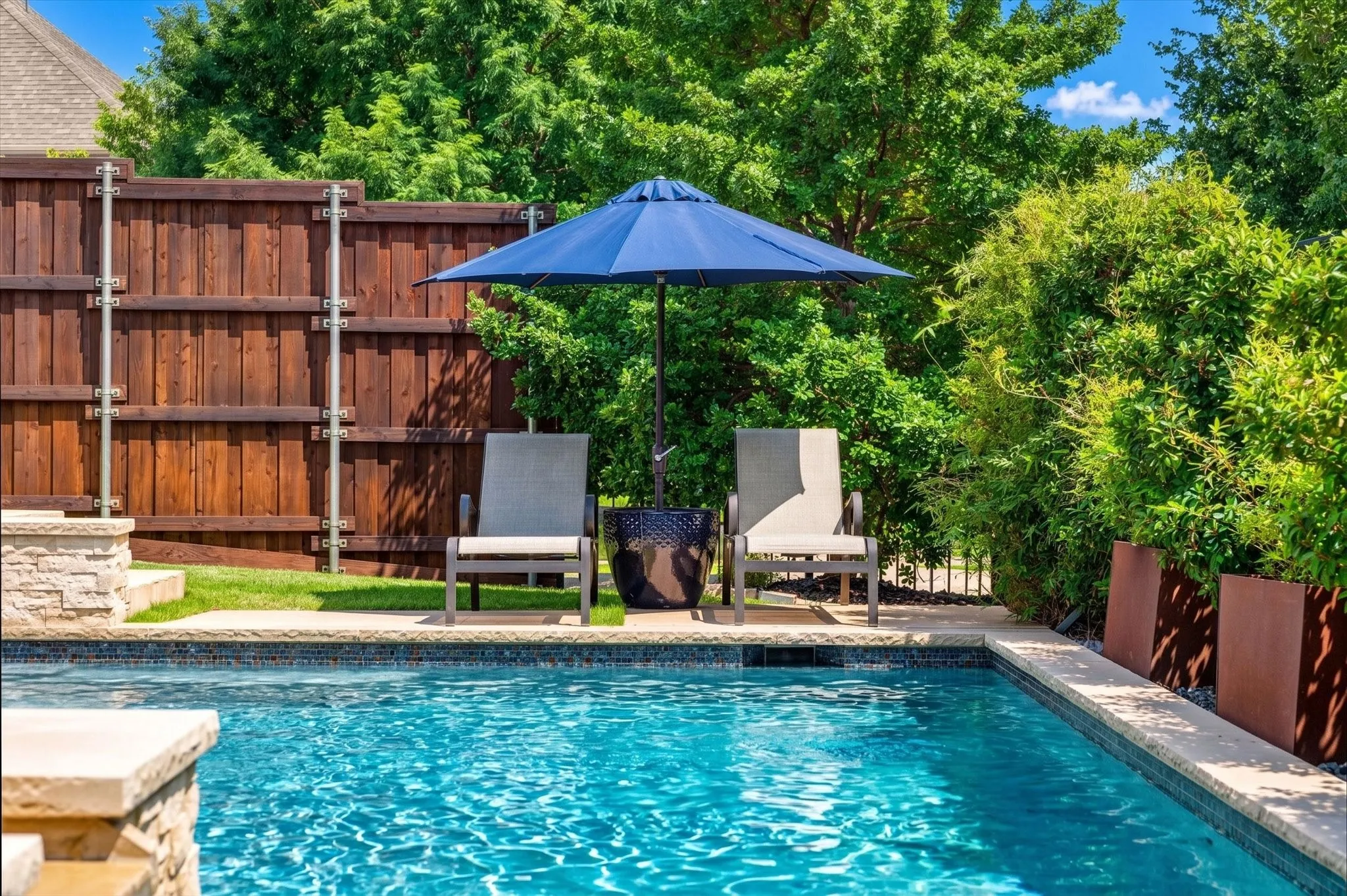 The waterfall chlorine pool includes a sun ledge and spa feature, creating a backyard escape that feels like vacation without airport security.