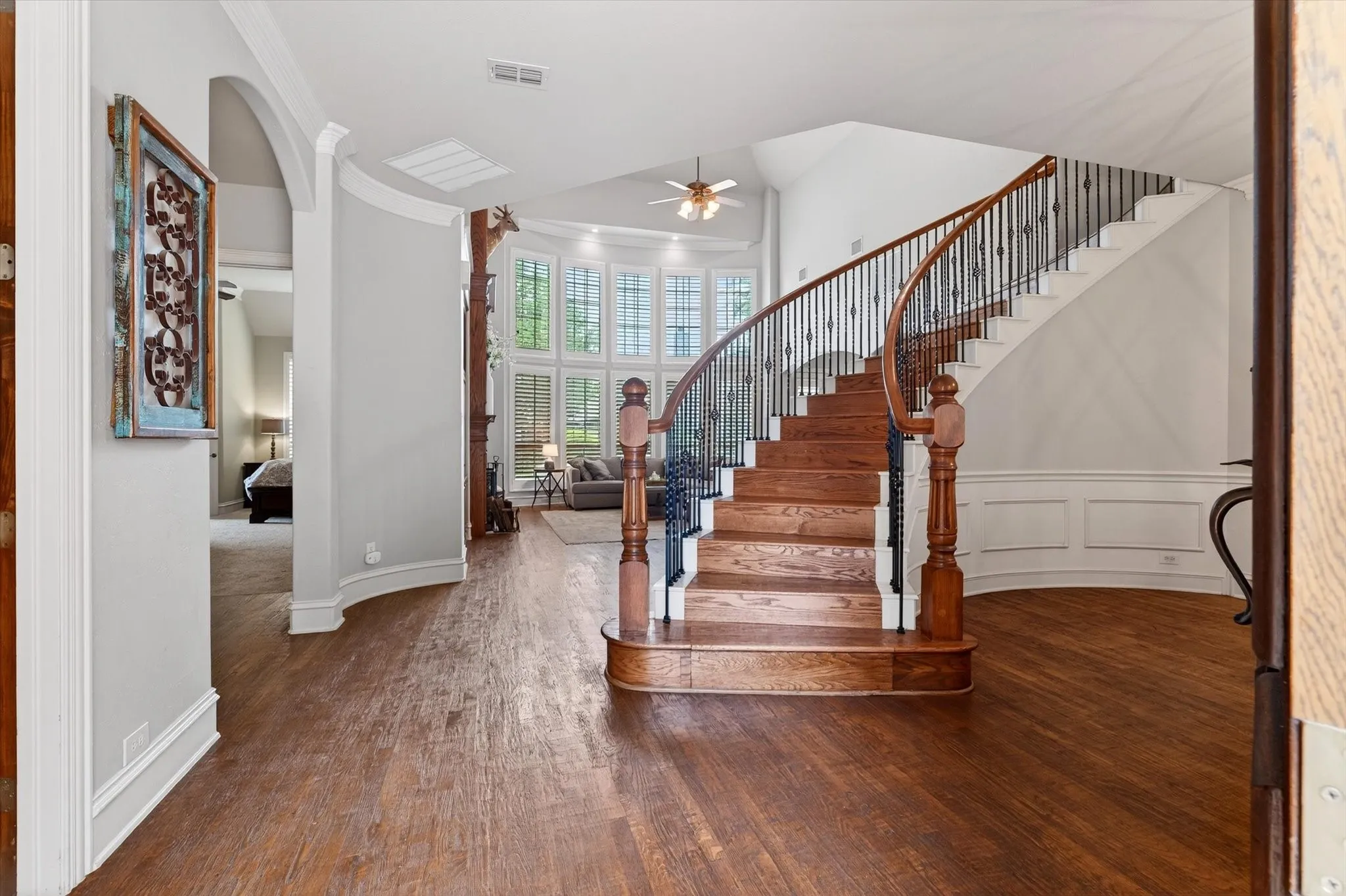 A dramatic entry sets the tone with hand-scraped hardwood floors, a sweeping staircase, iron spindles, and a layout that feels grand without trying too hard. Imagine that.
