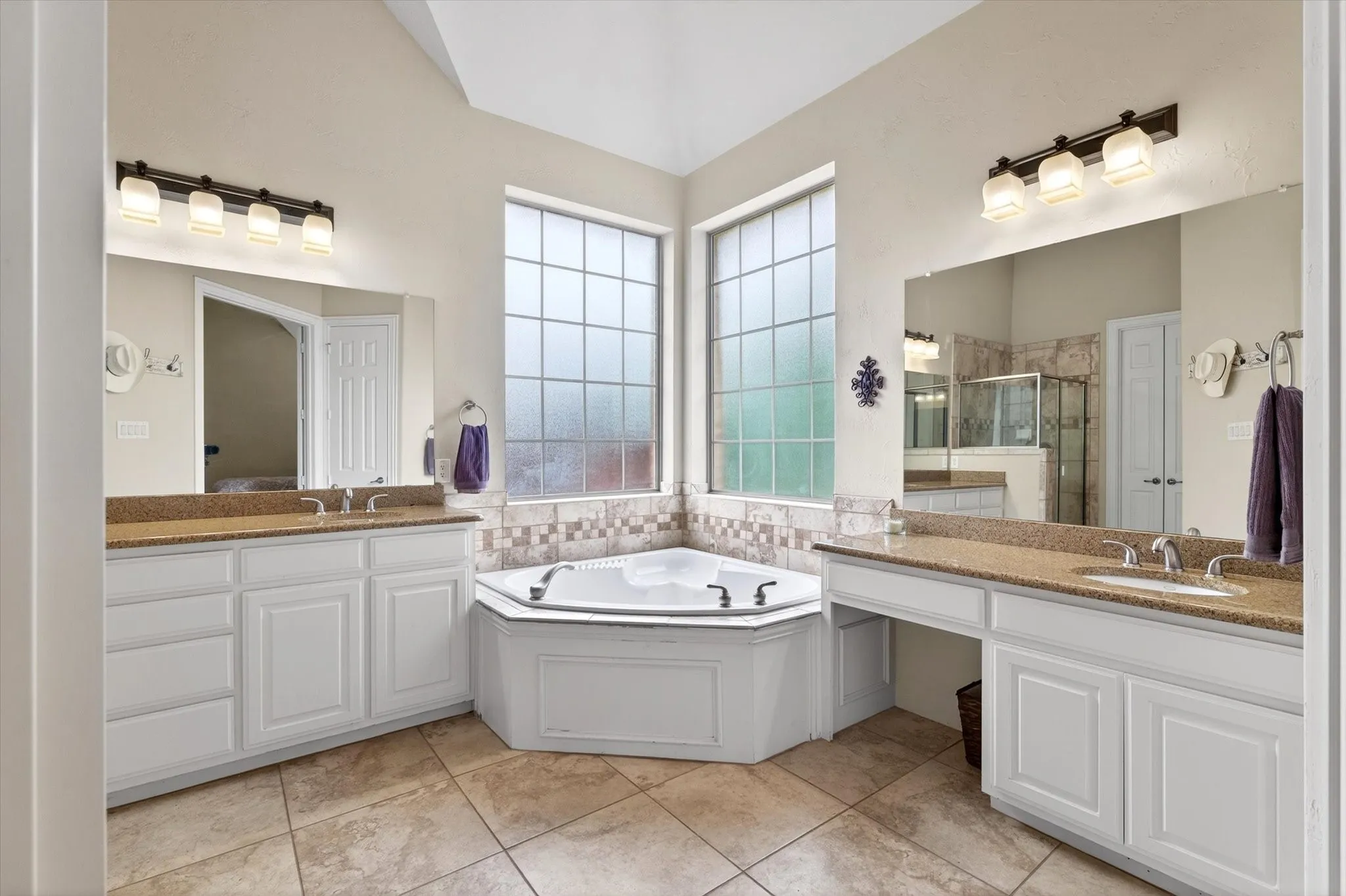 Dual vanities, framed mirrors, a soaking tub, separate shower, and great storage create a comfortable primary bath retreat.
