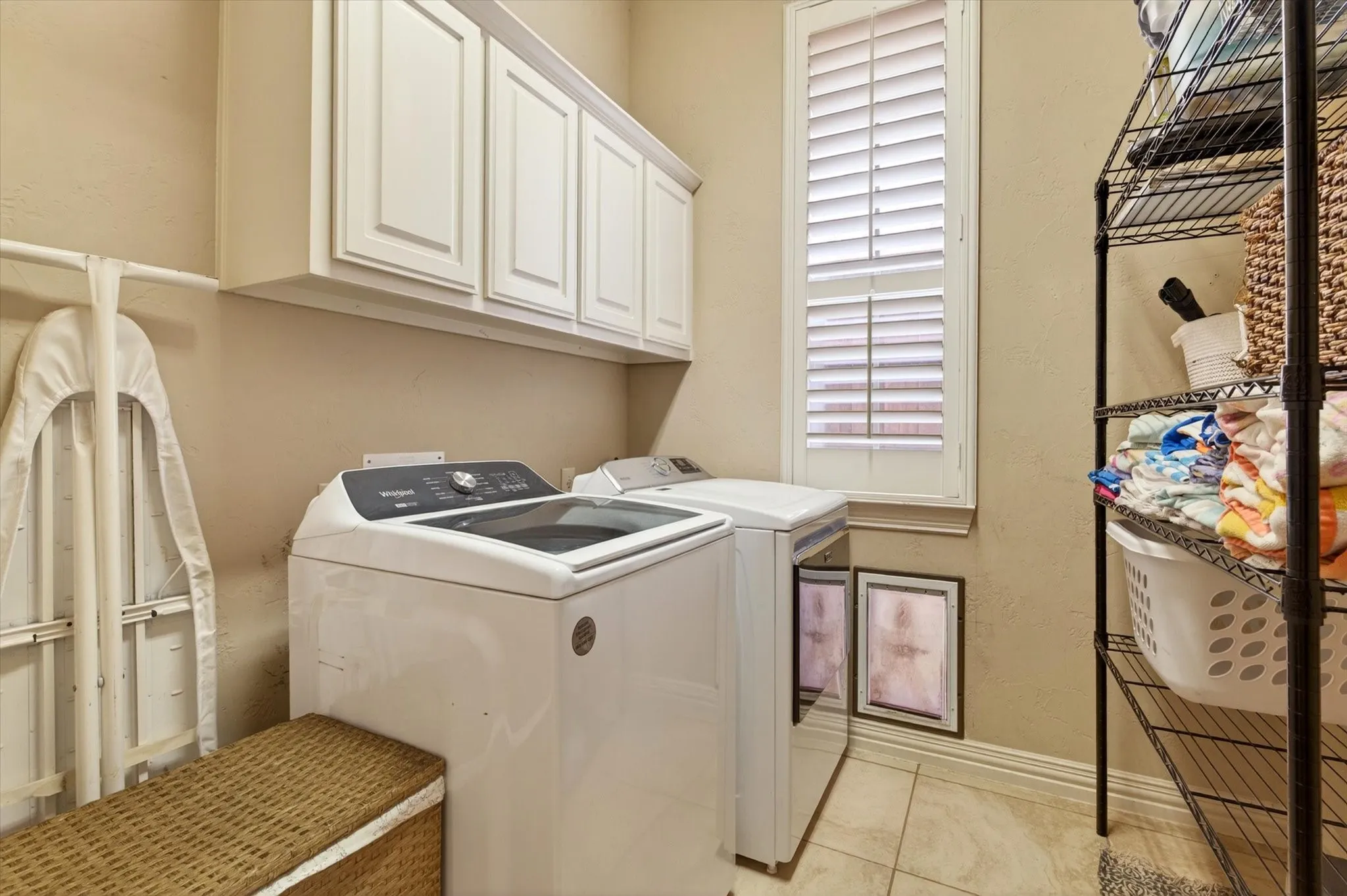 The laundry room includes cabinets, hanging space, a closet, and doggie door access, because real life requires more than one sad wire shelf.
