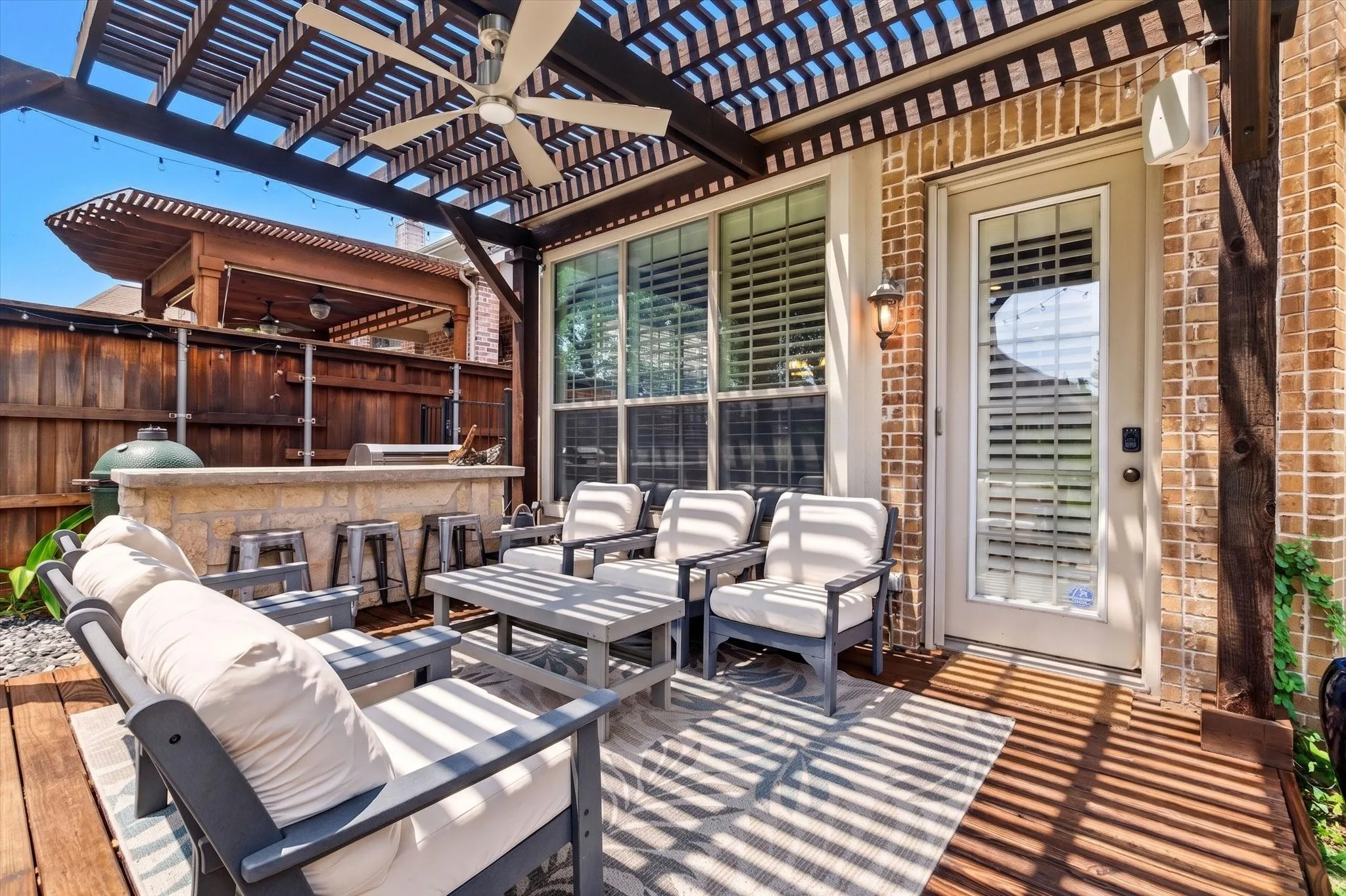 The outdoor living area features a pergola cover, gas grill, refrigerator, and poolside space made for entertaining.
