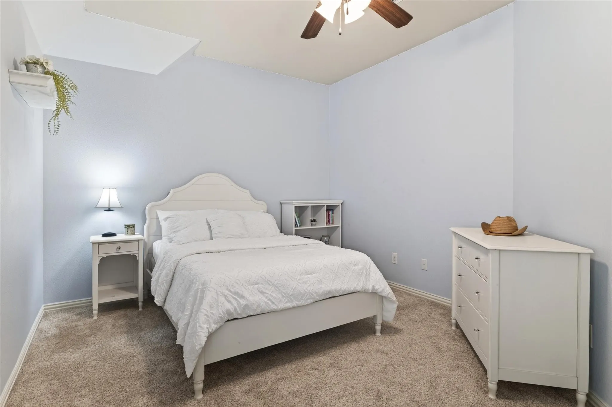 This upstairs bedroom feels light and inviting with vaulted ceilings, plantation shutters, and a walk-in closet.