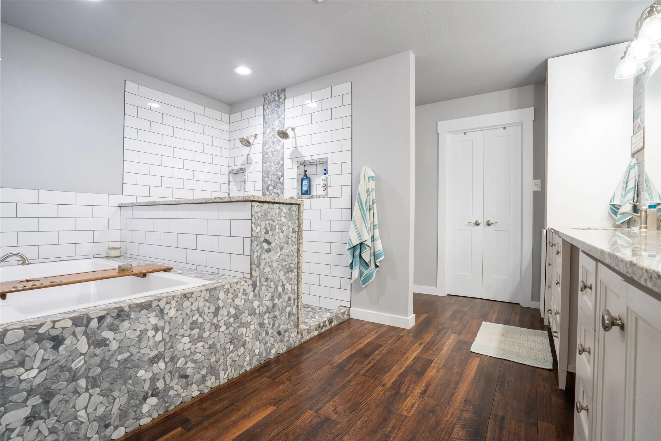 Spacious master bathroom featuring a white subway tile shower with dual showerheads and recessed niches