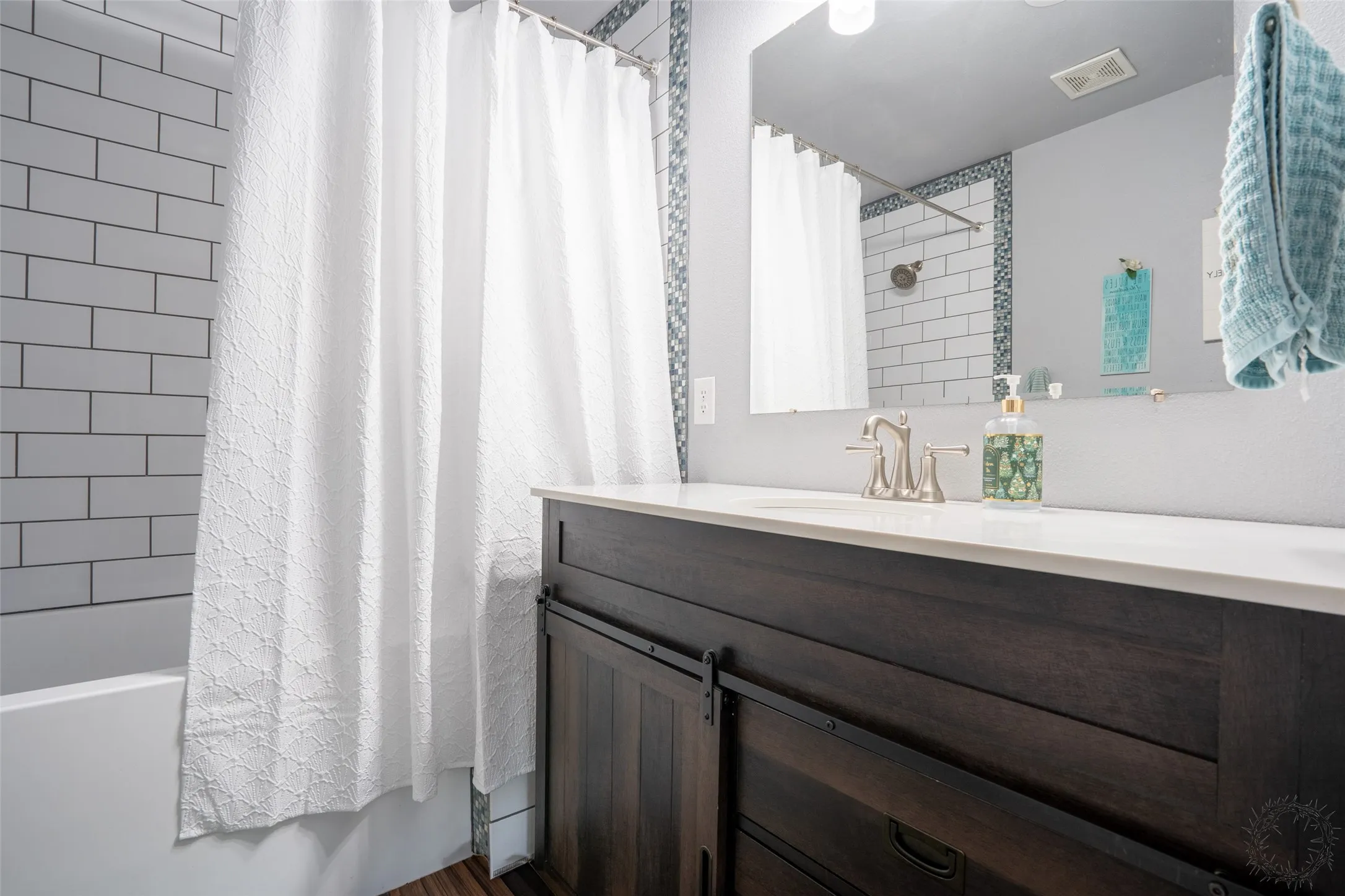 Bathroom featuring a dark wood-finish vanity with a white countertop and barn door-style cabinet fronts