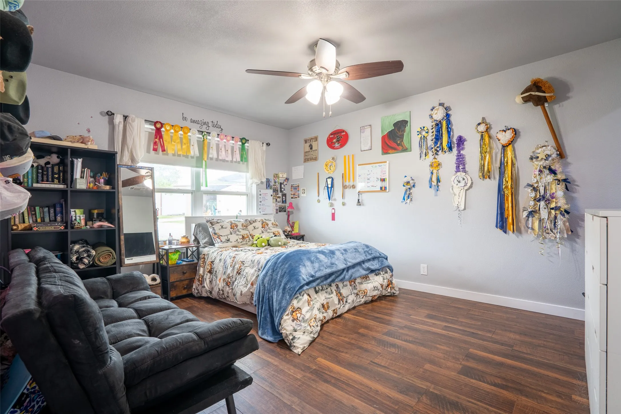Bedroom featuring wood-finish flooring, a ceiling fan with integrated lighting, and a window with white trim